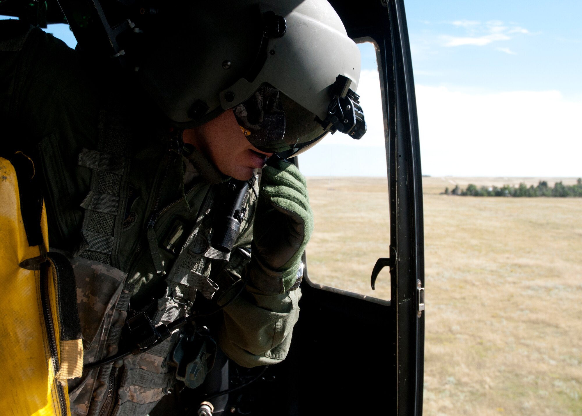 Master Sgt. Brent Bushey, 37th Helicopter Squadron, broadcasts a message to the pilots in his helicopter Aug. 25, 2014. While inside the cabin of the UH-1N Helicopter, Bushey operated the hoist and secured the passengers.