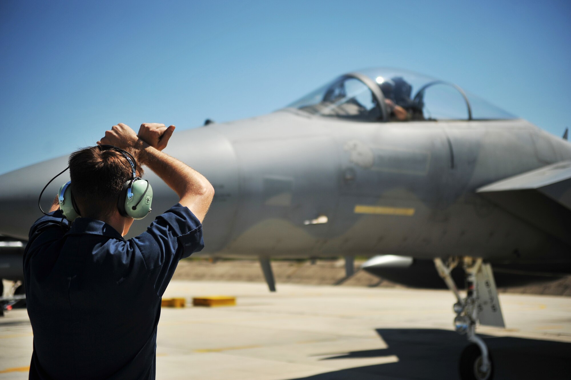 Senior Airman Skylar Richards, 493rd Aircraft Maintenance Unit crew chief, marshals an F-15C Eagle out of its parking spot at Graf Ignatievo Air Base near Plovdiv, Bulgaria, Aug. 19, 2014. There are many duties a crew chief preforms, one of them being to ensure the pilot taxis in and out of their parking spot safely. (U.S. Air Force photo/Senior Airman Hailey Haux)