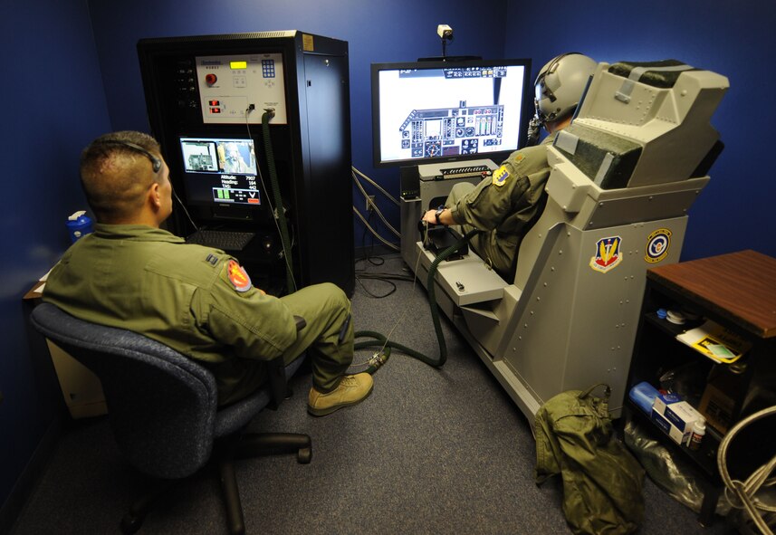 U.S. Air Force Capt. Ezekiel Duran, left, 7th Aerospace Medicine Squadron, and Maj. Shawn Hall, 34th Bomb Squadron, fly a training simulator mission while connected to a reduced oxygen breathing device (ROBD) Aug. 8, 2014, at Dyess Air Force Base, Texas. The ROBD induces the symptoms of oxygen deprivation that can occur at high altitudes and is used during hypoxia refresher training. (U.S. Air Force photo by Airman 1st Class Kylsee Wisseman/Released)
