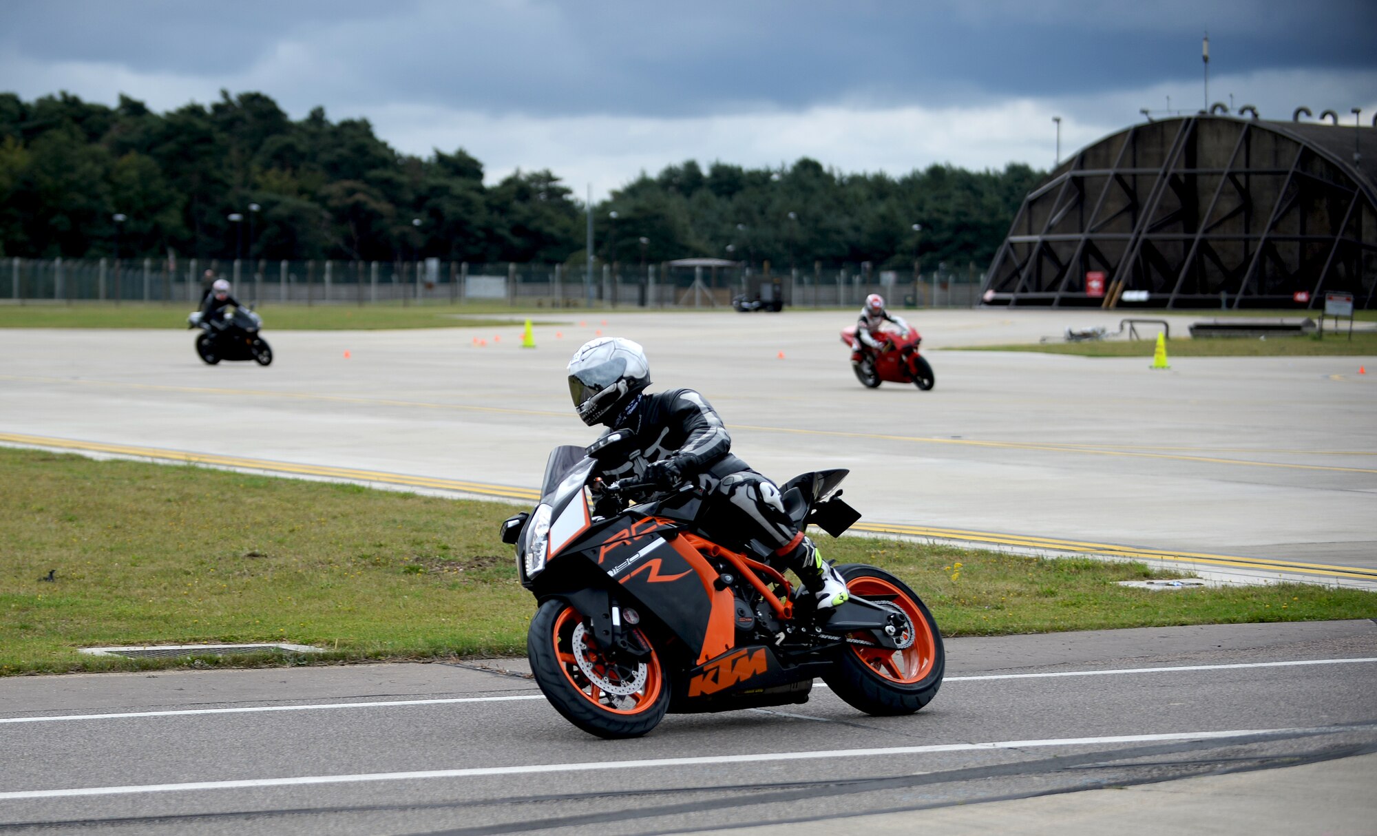 Motorcyclists ride through a closed course on the flightline during a motorcycle cornering event at Royal Air Force Lakenheath, Aug. 22, 2014. The cornering event was held to sharpen riders’ motorcycling skills to help riders become more familiar with their motorcycle’s capabilities and practice on roads similar to the surrounding area. (U.S. Air Force Photo by Staff Sgt. Emerson Nuñez/Released)