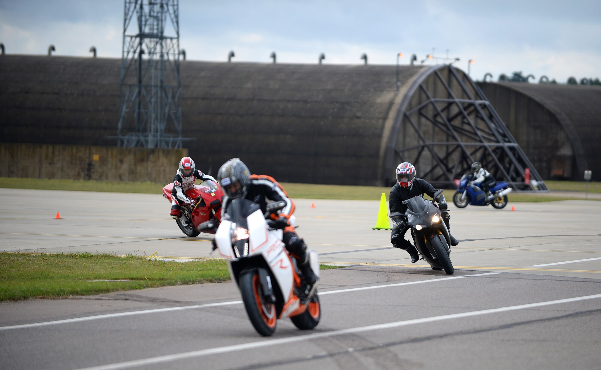 Motorcyclists ride through a closed course on the flightline during a motorcycle cornering event at Royal Air Force Lakenheath, Aug. 22, 2014. The cornering event was held to sharpen riders’ motorcycling skills to help riders become more familiar with their motorcycle’s capabilities and practice on roads similar to the surrounding area. (U.S. Air Force Photo by Staff Sgt. Emerson Nuñez/Released)