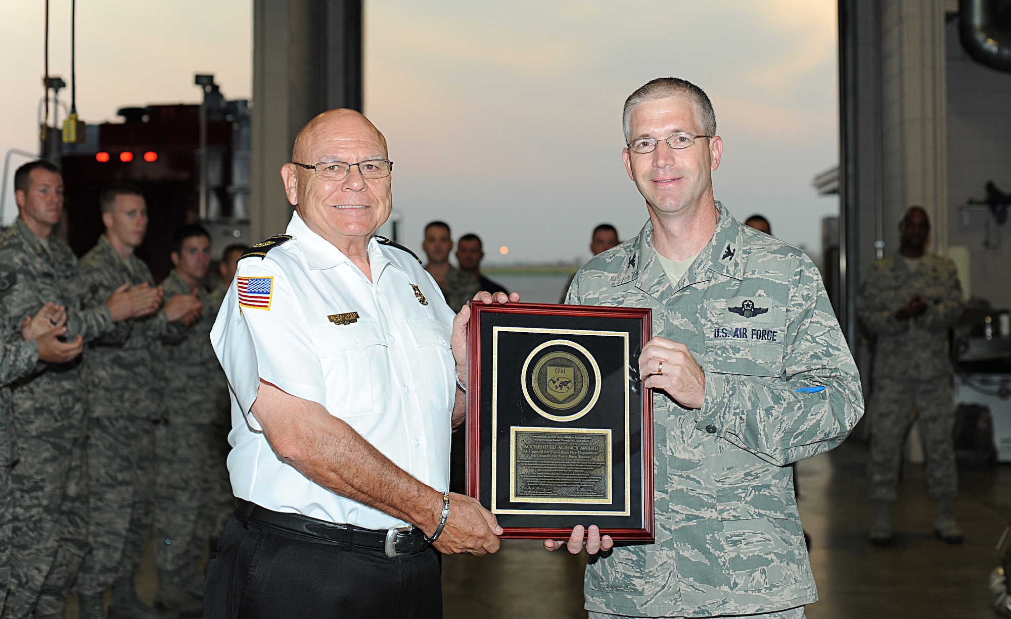 Col. Joel Jackson, 22nd Air Refueling Wing commander, presents the Accredited Agency Award to Charles Hutson, 22nd Civil Engineer Squadron fire chief, Aug. 27, 2014, at McConnell Air Force Base, Kan. McConnell’s Fire and Emergency Services Flight earned its accreditation, Aug. 13, 2014, from the Commission on Fire Accreditation International. (U.S. Air Force photo/Airman 1st Class David Bernal Del Agua)