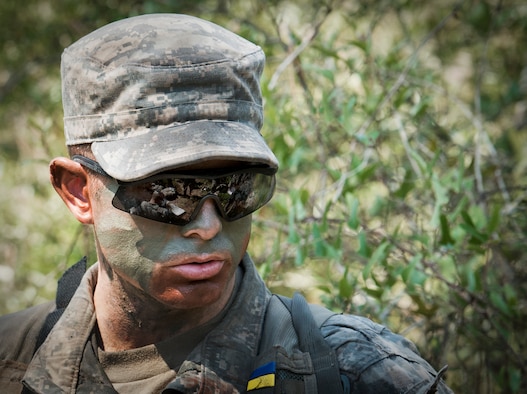 An Army Ranger student watches as Soldiers discuss strategy before an upcoming maneuver in the woods of the Eglin Air Force Base, Fla., range.  Students complete the final phase of the Army Ranger course with the 6th Ranger Training Battalion.  Instructors expose the students to 18-day field training that includes airborne and helicopter assaults, small boat operations, river and swamp crossings.  (U.S. Air Force photo/Tech. Sgt. Samuel King Jr.)