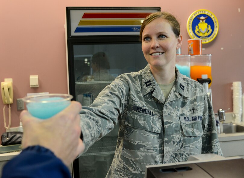 Capt Jayme Kendall, 91st Missile Wing Chaplain, hands a slushy to an Airman at the chapel’s free coffee and slushy counter in the McAdoo Sports and Fitness Center on Minot Air Force Base, N.D., Aug. 5, 2014. The counter is open from 7:30 a.m. to 9 a.m. Tuesday, Wednesday and Thursday, and offers a variety of free coffee, hot cocoa and two flavors of sports-drink slushies. (U.S. Air Force photo/ Senior Airman Stephanie Morris)