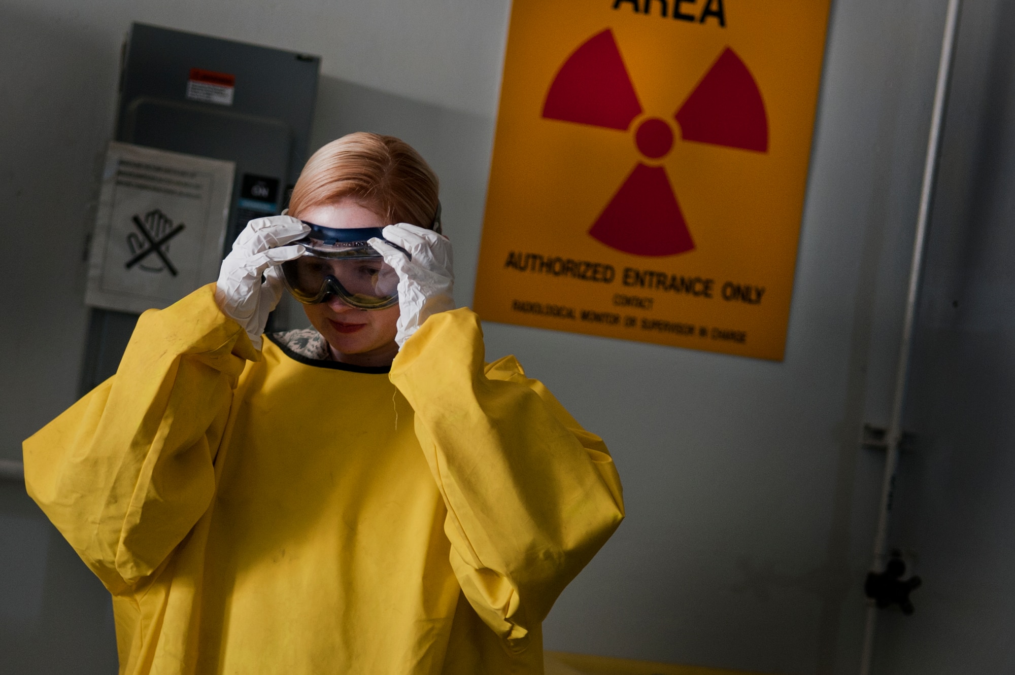 Airman 1st Class Courtney Harrah, 5th Maintenance Squadron non-destructive inspection apprentice, dons her personal protective equipment before performing a cracked chrome panel test for the stationary fluorescent penetrant inspection line.  (U.S. Air Force photo/Senior Airman Brittany Y. Bateman)