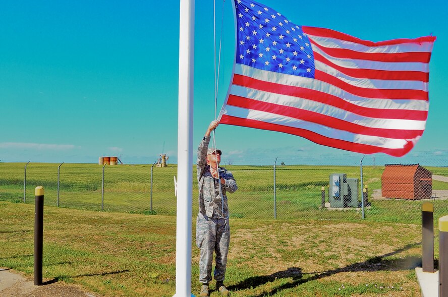 Tech. Sgt. Kevin McPherson, 91st Operations Group superintendent of missile alert facility management, takes down the flag at a MAF in North Dakota. Each day FMs check water levels and the launch control equipment building to ensure everything is working properly. (U.S. Air Force photo/Senior Airman Brittany Y. Bateman)