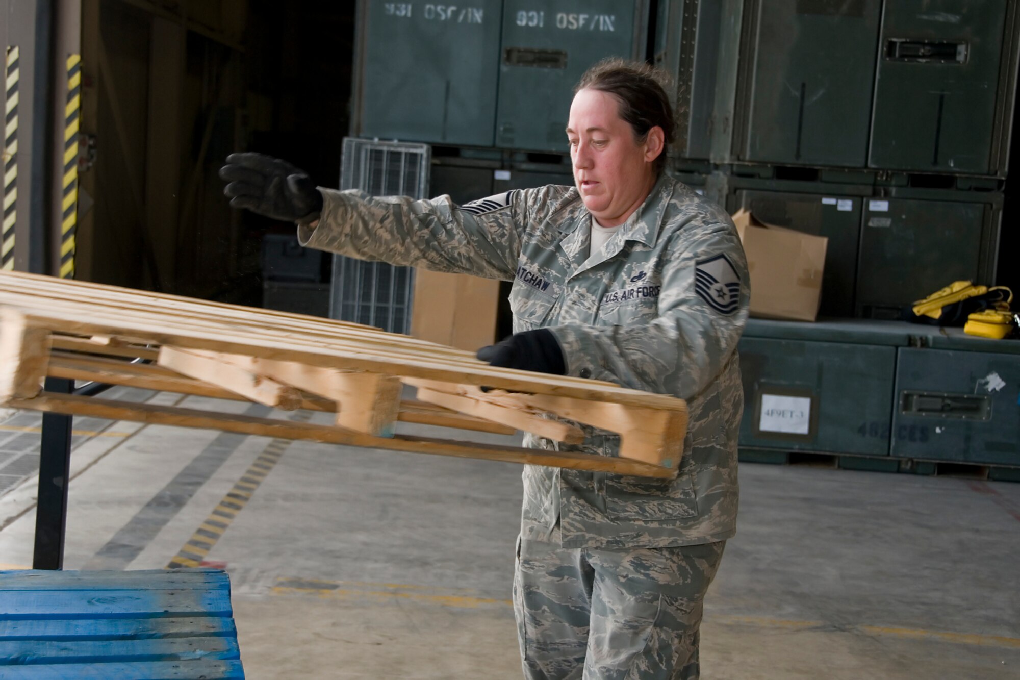 Master Sgt. Laurie Latchaw, 49th Aerial Port Flight deputy superintendent, stacks used pallets as she and her team of reservists prepare to ship cargo overseas aboard a KC-10 Extender aircraft at Grissom Air Reserve base, Ind., Aug 9, 2014. Grissom Air Force reservists teamed up with Airmen from Charleston Air Force Base, S.C., to deliver 91,000 pounds of food, clothes and supplies to Haiti as part of a humanitarian relief mission under the Denton Program. (U.S. Air Force photo/Senior Airman Jami K. Lancette)