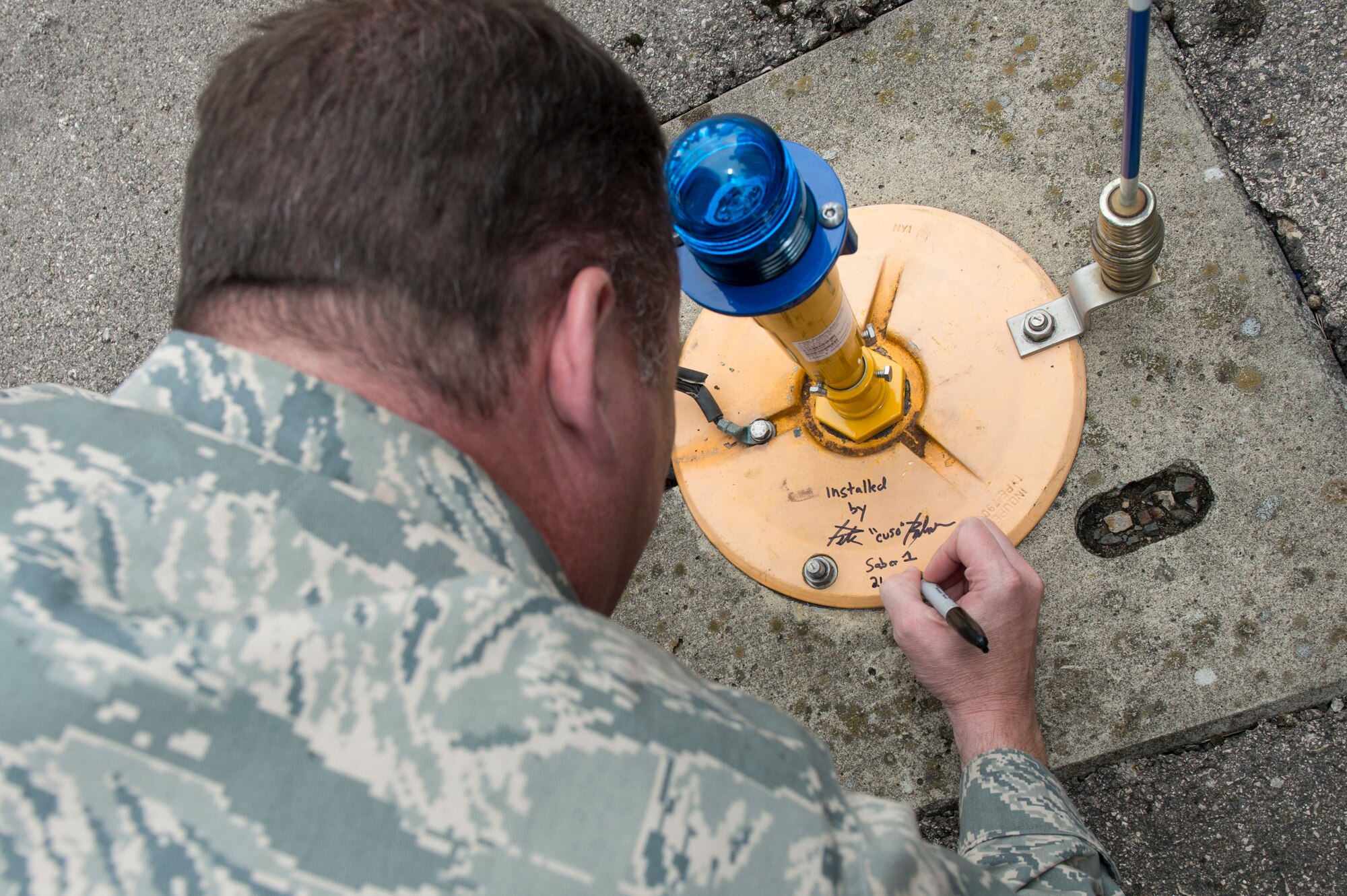 U.S. Air Force Col. Pete Bilodeau, 52nd Fighter Wing commander, places his signature on the taxiway light he helped replace with the 52nd Civil Engineer Squadron, Aug. 26, 2014, at Spangdahlem Air Base, Germany. More than 1,000 taxiway lights have been upgraded to the energy efficient Light-Emitting Diode. (U.S. Air Force photo by Staff Sgt. Christopher Ruano/Released)
