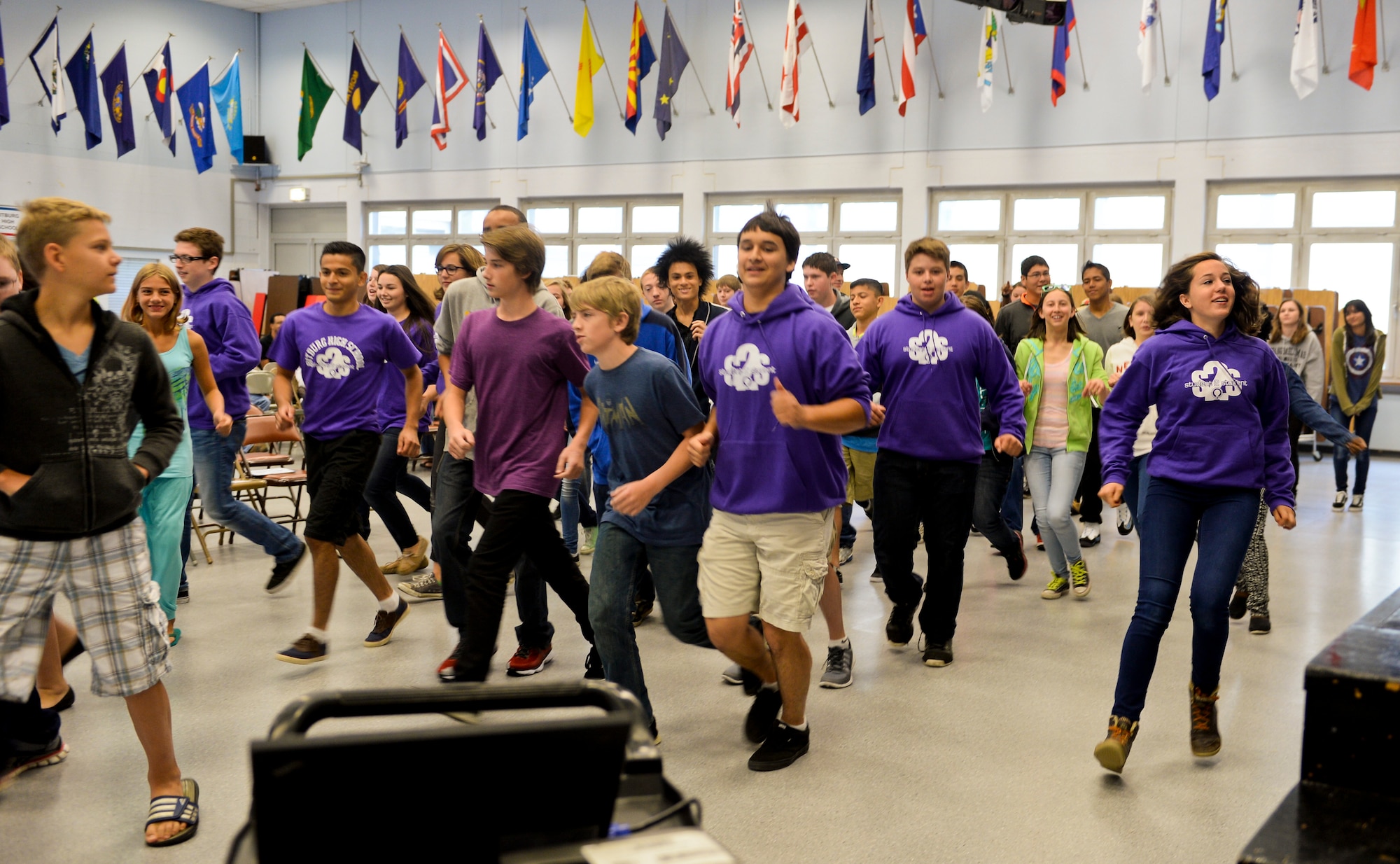 Student 2 Student members and newcomers play a social game at the S2S orientation event in the school auditorium at Bitburg Annex, Germany, Aug. 22, 2014. The S2S members hosted the orientation to integrate incoming students before the start of the school year. (U.S. Air Force photo by Airman 1st Class Timothy Kim/Released)