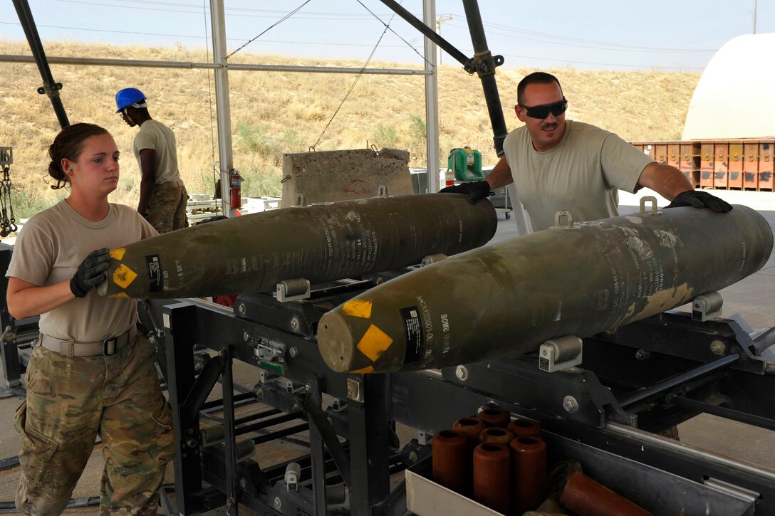 U.S. Air Force Airman 1st Class Casey Cain, left, and U.S. Air Force Senior Airman Christopher Reed slide a GBU-38 bomb onto a conveyor during a bomb build on Bagram Airfield, Afghanistan, Aug. 14, 2014. Cain and Reed are munitions systems technicians assigned to the 455th Expeditionary Maintenance Squadron.