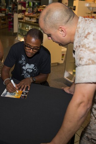 Tommy Davidson, an entertainer with Kenny Hill’s All Star Comedy Slam, autographs a pamphlet for Master Sgt. Raul Concepcion, the brig officer with the Provost Marshal’s Office, inside the Marine Corps Exchange aboard Marine Corps Air Station Iwakuni, Japan, Aug. 26, 2014. As part of the comedy slam, Davidson is slated to tour the air station, as well as performing a live comedy show inside Club Iwakuni.    