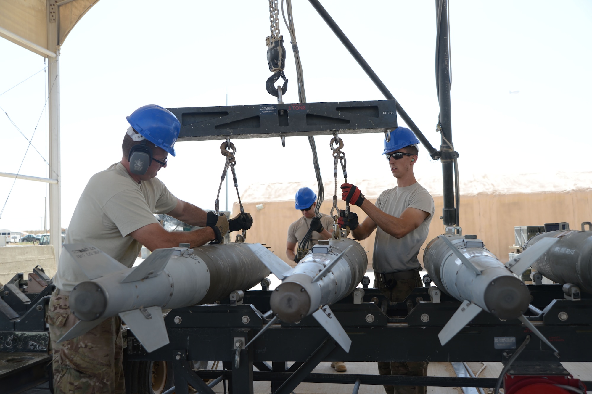 Tech. Sgt. Patrick Williams (left) and Senior Airman Brandon Graves attach GBU-38 bombs to a hoist that will be used with a munitions assembly conveyer to move the bombs during transport Aug. 14, 2014, at Bagram Airfield in support of Operation Enduring Freedom.  Both men are currently assigned to the 455th Expeditionary Maintenance Squadron and both are reservists deployed from the 442nd Fighter Wing, Whiteman Air Force Base, Mo. (U.S. Air Force photo by Master Sgt. Cohen A. Young)
