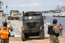 VIRGINIA BEACH, Va. (Aug. 27, 2014) – Sailors with Beachmaster Unit 2, Naval Beach Group Two, guide Sgt. William Anderson, a motor transportation operator with Transport Support, Combat Logistics Battalion 26 onto an Improved Navy Lighterage System (INLS) during a loading exercise (LOADEX) aboard Joint Expeditionary Base Little Creek Aug. 27. The LOADEX was designed to simulate a Defense Support to Civil Authorities (DSCA) mission, in order to train the Marines and Sailors what they need to accomplish during an actual DSCA mission and identify and rectify any shortfalls before the event of a real-world mission. A DSCA mission would occur if a federal agency, on behalf of local civil authorities, made a request to the Department of Defense to fill specific gaps in their abilities to respond to a natural or man-made disaster. (U.S. Marine Corps photo by Staff Sgt. Scott McAdam/Released)