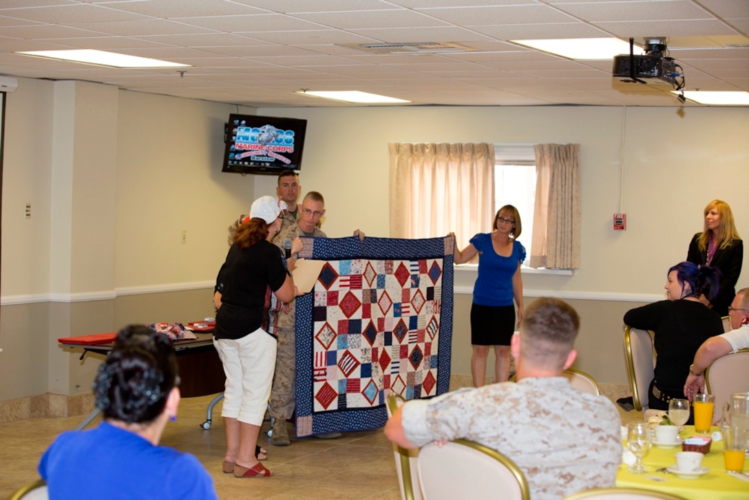 Sergeant Steven B. Waddell, with Fleet Support Division, Production Plant Barstow, receives a quilt from Quilts of Valor during Quarterly Awards breakfast, Aug., 20. Quilts of Valor volunteers make quilts for deserving service members around the world. 