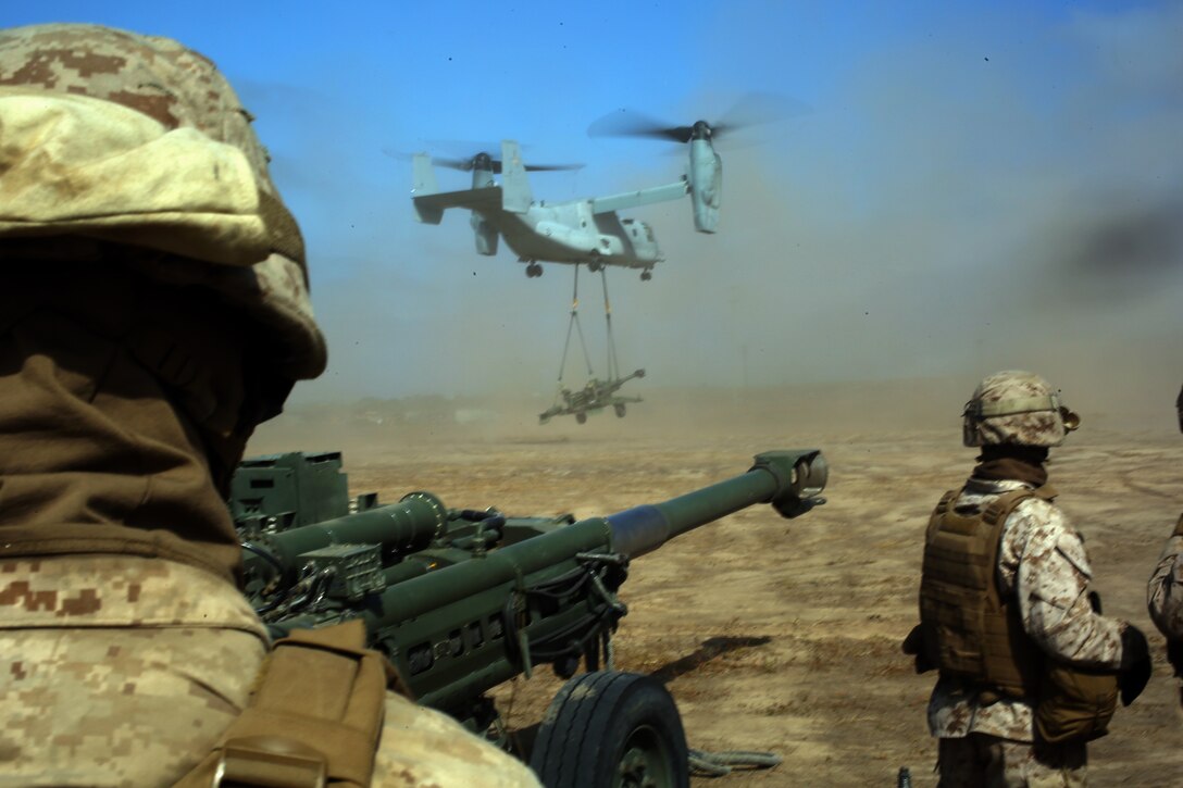 Landing support Marines, with Combat Logistics Battalion 13, 1st Marine Division watch as an MV-22 conducts an external lift of a M777A2 lightweight howitzer in support of the summer firing exercise, August 21, 2014, aboard Camp Pendleton, California. The 11th Marines conducted an eight-day firing exercise where they maneuvered and fired upon multiple ranges. For two days, the Marines trained for internal embarkation of the 120 mm mortar and the external lift of the howitzer. 