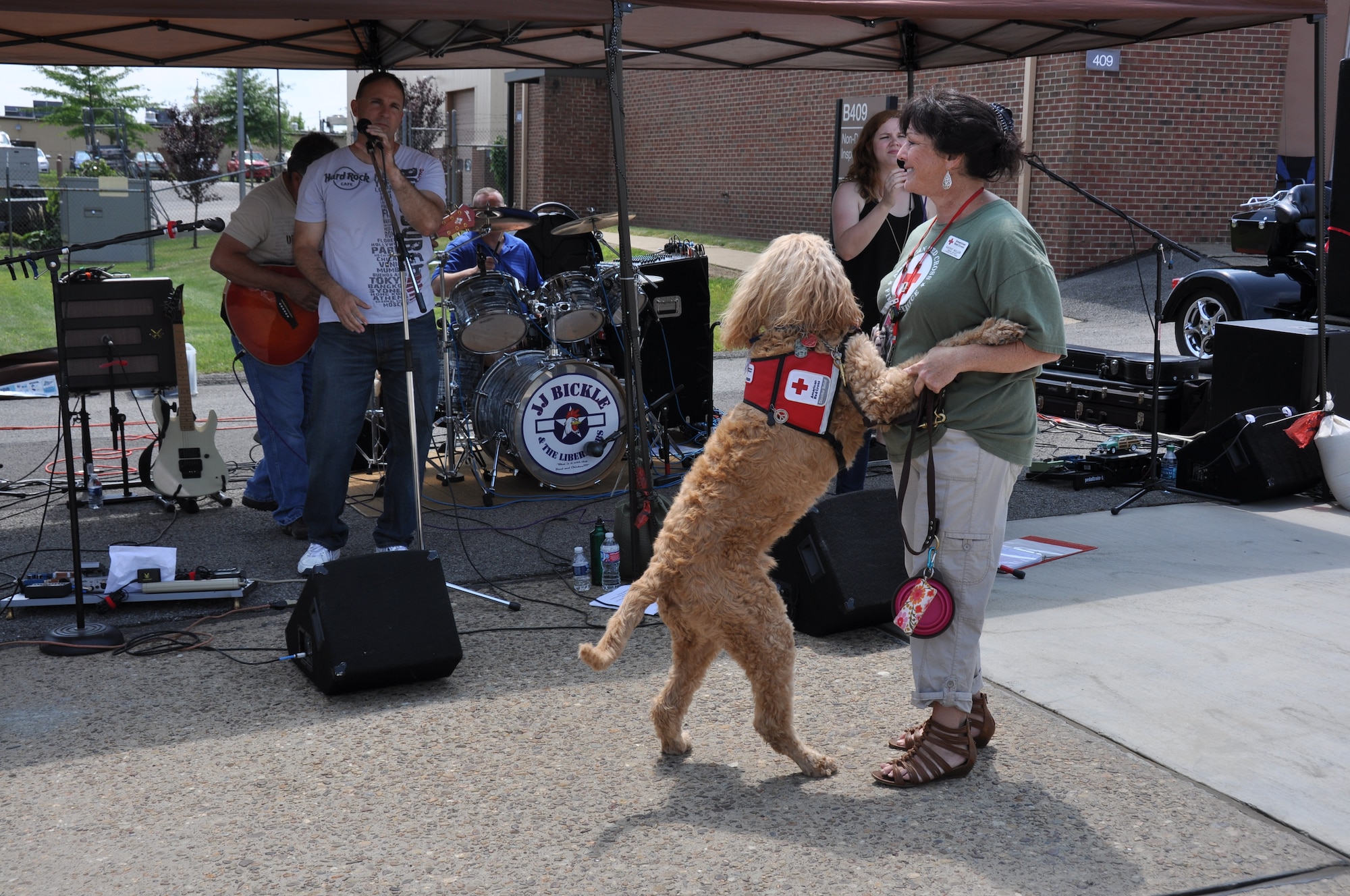 Gus, a therapy dog with the American Red Cross K9 Action Team, dances with his handler Kathy Miller during a performance by JJ Bickle and the Liberators at the Pittsburgh International Airport Air Reserve Station, August 2, 2014. (U.S. Air Force photo by Senior Airman Marjorie A. Bowlden)