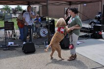 Gus, a therapy dog with the American Red Cross K9 Action Team, dances with his handler Kathy Miller during a performance by JJ Bickle and the Liberators at the Pittsburgh International Airport Air Reserve Station, August 2, 2014. (U.S. Air Force photo by Senior Airman Marjorie A. Bowlden)