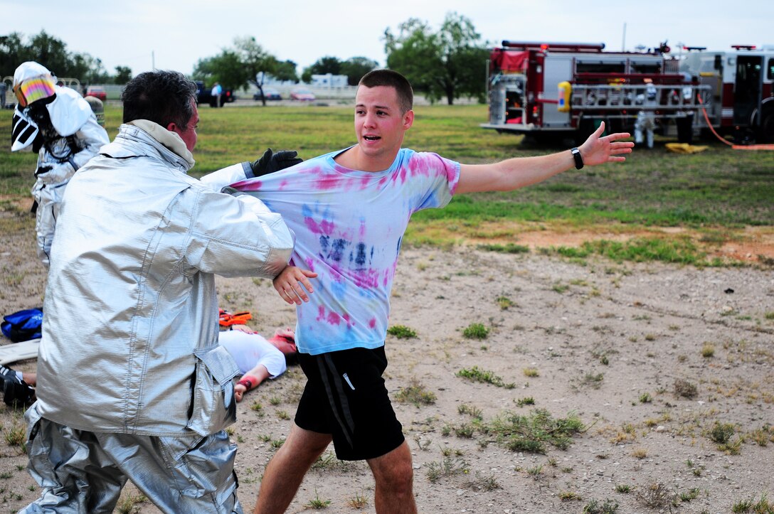 Role player 2nd Lt. Keith Stock, 47th Student Squadron student pilot, attempts to comfort his friend in a scenario on Laughlin Air Force Base, Texas, Aug. 20, 2014. Role players, a critical asset in a training environment, provide a freethinking, adaptive, capabilities-based force to act as "cast members" during active component training events, helping to create a realistic and unique experience. (U.S. Air Force Photo by Staff Sgt. Steven R. Doty)(Released)