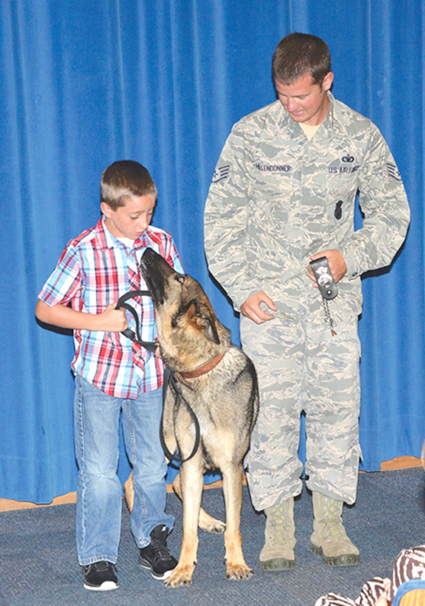 Brandon Wilson gets a good look at his new pet, Dan, a retiring military working dog. Wilson’s father, Tech. Sgt. Daniel Wilson, served with the working dog and credits him with saving his life in combat. (Photo by Dennis Carlson) 