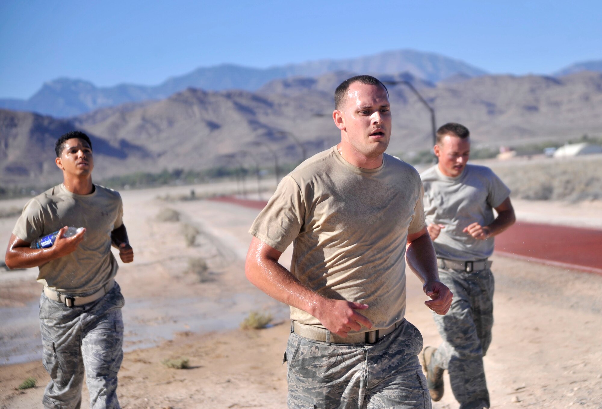 Tech. Sgt. Michael McGuire, 99th Contracting Squadron contracting specialist, left, Staff Sgt. James Eustace, 99th CONS contracting specialist, center, Staff Sgt. Derek Urban, 99th CONS contracting specialist, run toward the last obstacle of the Warrior Challenge after getting sprayed with water during the first-ever Warrior Challenge Aug. 22, 2014, on Creech Air Force Base, Nev. The Warrior Challenge is part of the Life of a Warrior campaign which aims to promote the four pillars of resiliency for those who participate. (U.S. Air Force photo by Airman 1st Class Christian Clausen/Released)
