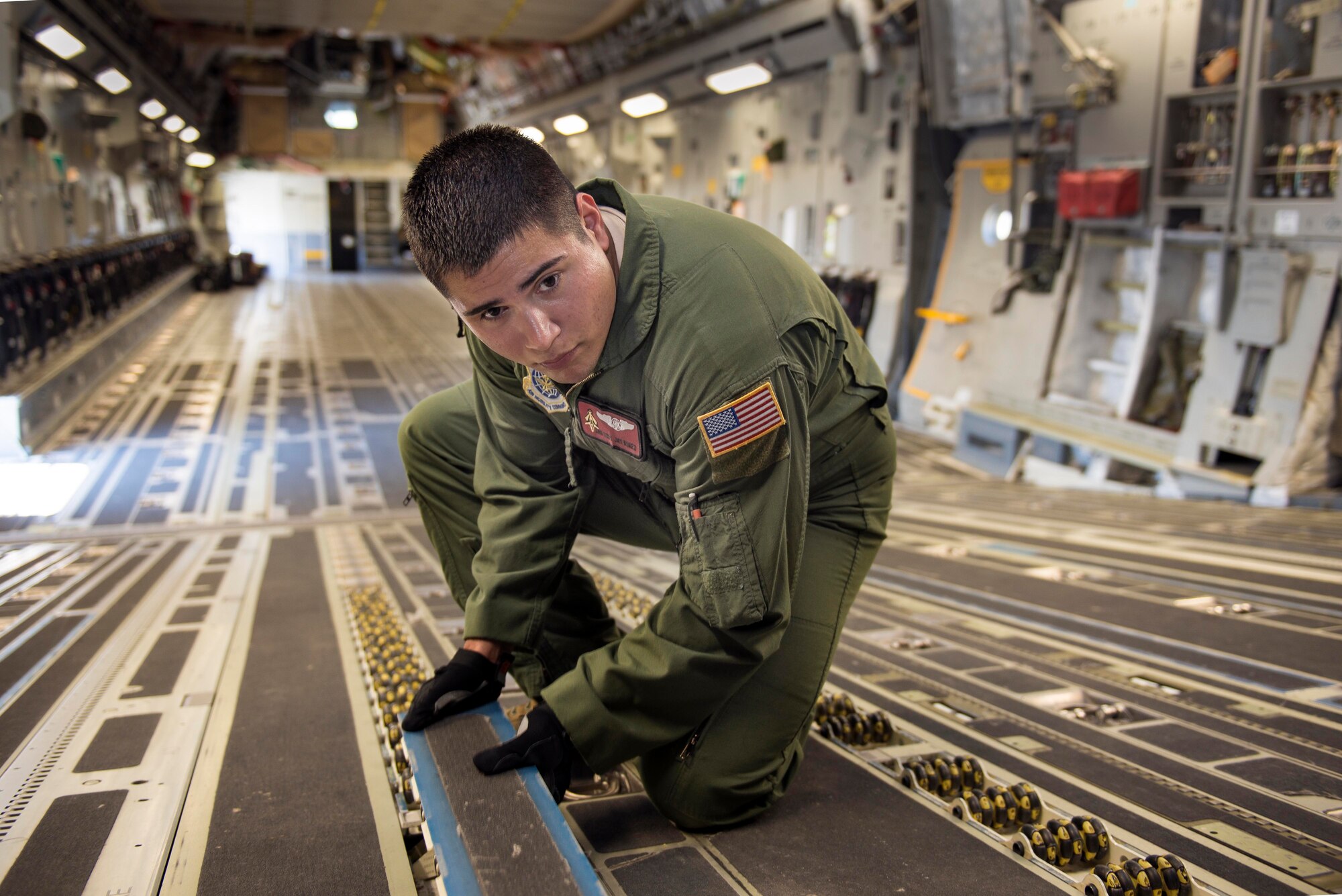 Senior Airman Cody Nuñez, 21st  Airlift Squadron loadmaster, prepares the cargo floor for palletized cargo Monday. Nuñez has been selected to receive the General P.K. Carlton Award for Valor for heroic activity in the medical evacuation of 3 Navy Seals out of Uganda. (U.S. Air Force Photo/Heide Couch)