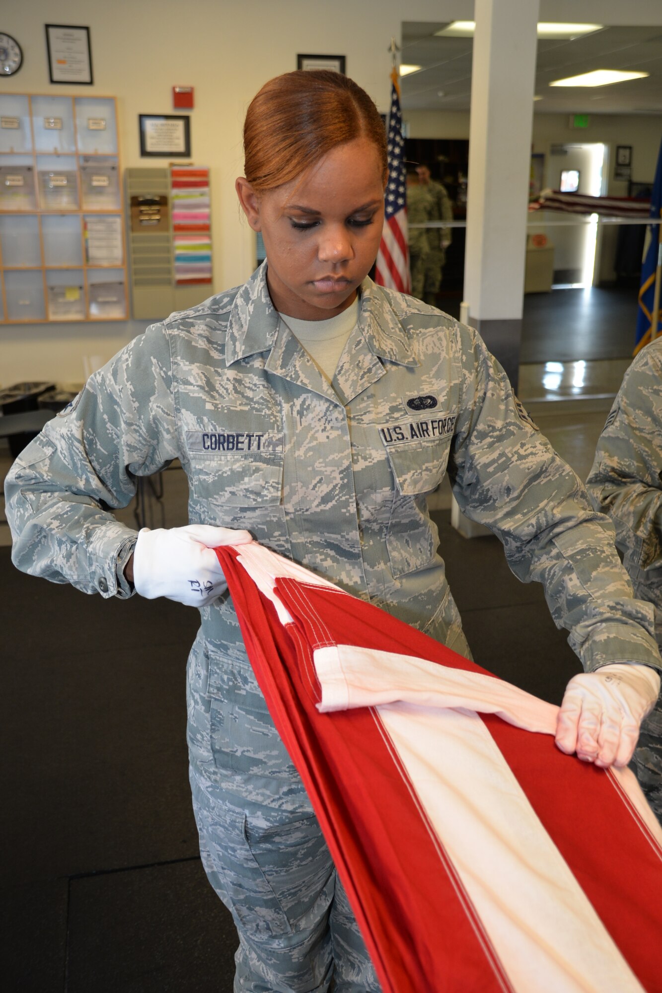 Senior Airman Siera Corbett, 349th Memorial Affairs Squadron, focuses on the finer details of performing a two-man flag fold during a week-long training with the Travis Honor Guard. The class consisted of 10 members of the 349th Air Mobility Wing to build up the wing’s honor guard team to perform colors details. (U.S. Air Force photo/Senior Airman Bryan Swink)