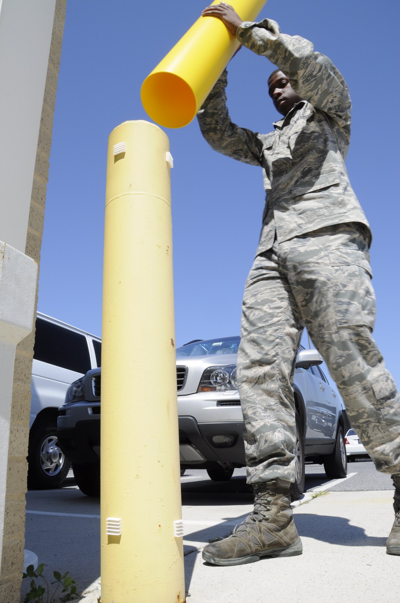 Senior Airman Christian Habersham puts a safety yellow pole sleeve on an existing safety pole outside the Charles C. Carson Center for Mortuary Affairs, Dover Air Force Base, Del., Aug. 25, 2014. The sleeve is one of many measures Air Force Mortuary Affairs Operations has implemented to enhance safety. Habersham is deployed to the mortuary from the 459th Force Support Squadron, Joint Base Andrews, Md. (U.S. Air Force photo Staff Sgt. Lucas Morrow)