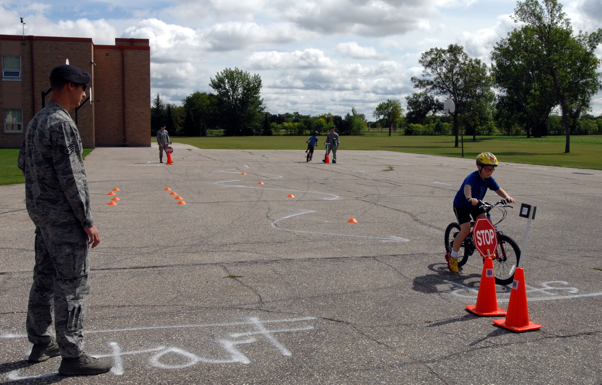 Staff Sgt. Ruben McMahon, 319th Security Forces Squadron, supervises children on a bike safety obstacle course Aug. 26, 2014, at the Kids’ Passport to Safety event held at Nathan F. Twining Elementary and Middle School on Grand Forks Air Force Base, N.D. There were also several information tables at the event that offered the school traffic plan for when school begins, as well as a carpooling directory, new school security guidelines, and supervision options for before and after school. (U.S. Air Force photo/Staff Sgt. Susan L. Davis)