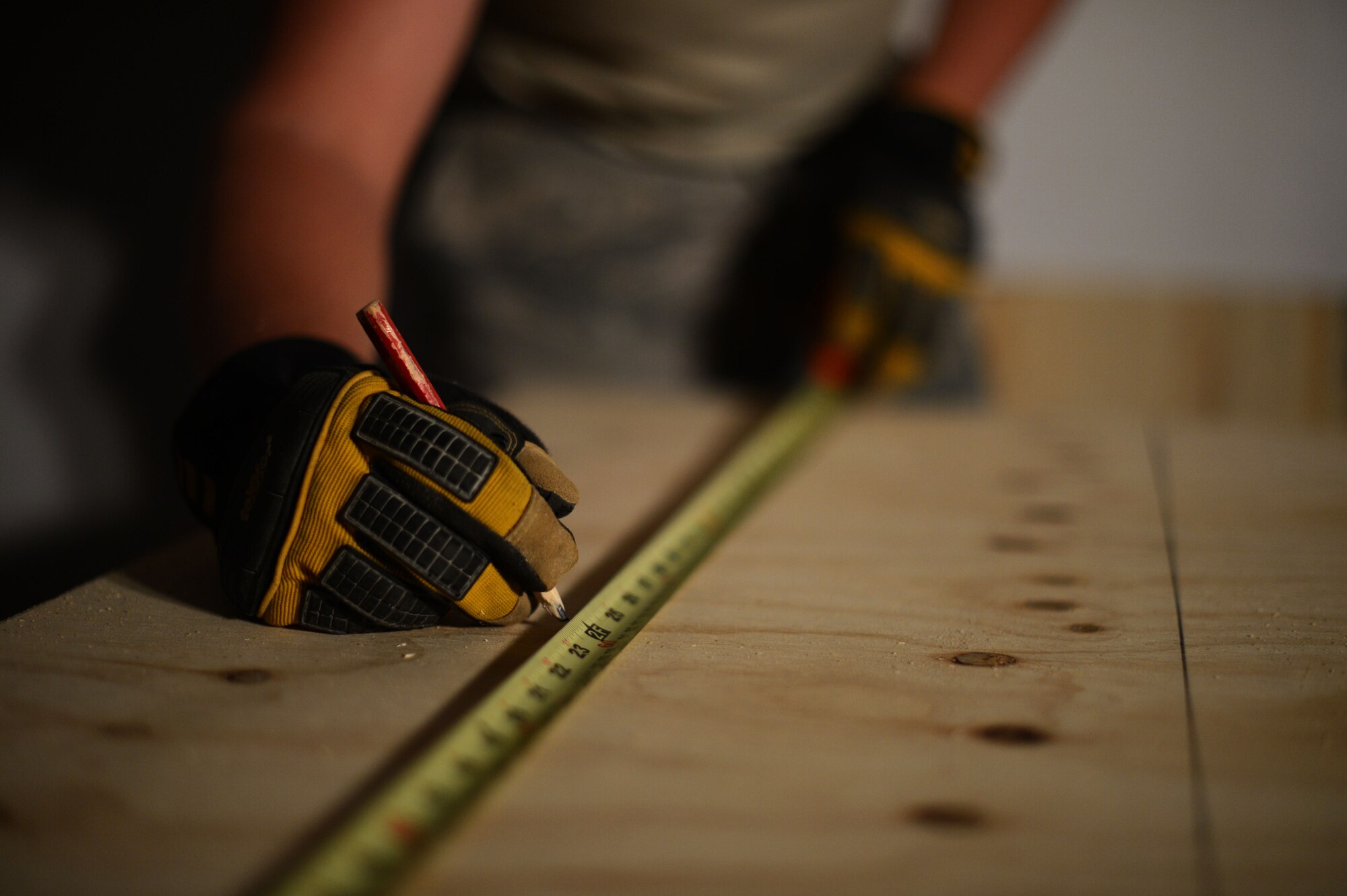 U.S. Air Force Airman 1st Class Lane Kocian, a 52nd Civil Engineer Squadron structures technician from Louise, Texas, marks the cutting path on a wooden sheet at a construction site inside the Skelton Memorial Fitness Center Aug. 26, 2014. Airmen must place marks in exact measurements to ensure the wooden reinforcements fit in their designated places on the wall. (U.S. Air Force photo by Senior Airman Gustavo Castillo/Released) 