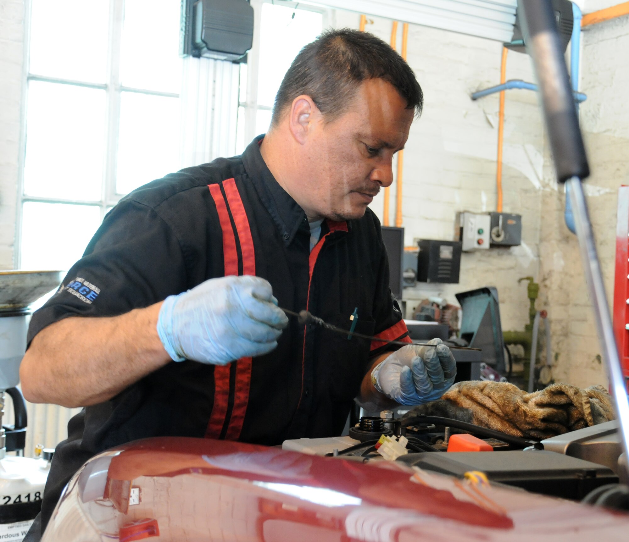Alejandro Soto, 100th Force Support Squadron auto hobby shop technician from McFarland, Calif., checks the dipstick of a vehicle Aug. 13, 2014, at the auto hobby shop on RAF Mildenhall, England. The dipstick measures how much oil is in the tank to insure the level is not too high or too low, which could result in irreversible damage to the engine. (U.S. Air Force photo/Gina Randall/Released)