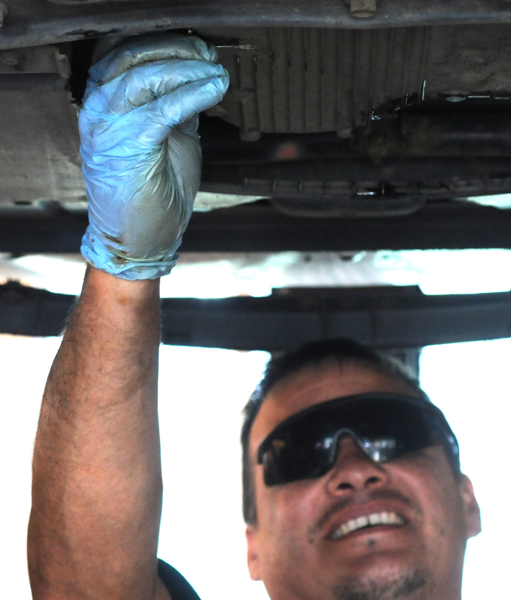 Alejandro Soto, 100th Force Support Squadron auto hobby shop technician from McFarland, Calif., unscrews an oil plug to change a vehicle’s oil Aug. 13, 2014, at the auto hobby shop on RAF Mildenhall, England. The auto hobby technicians change oil for service members and their dependents among other vehicle-related services. (U.S. Air Force photo/Gina Randall/Released)