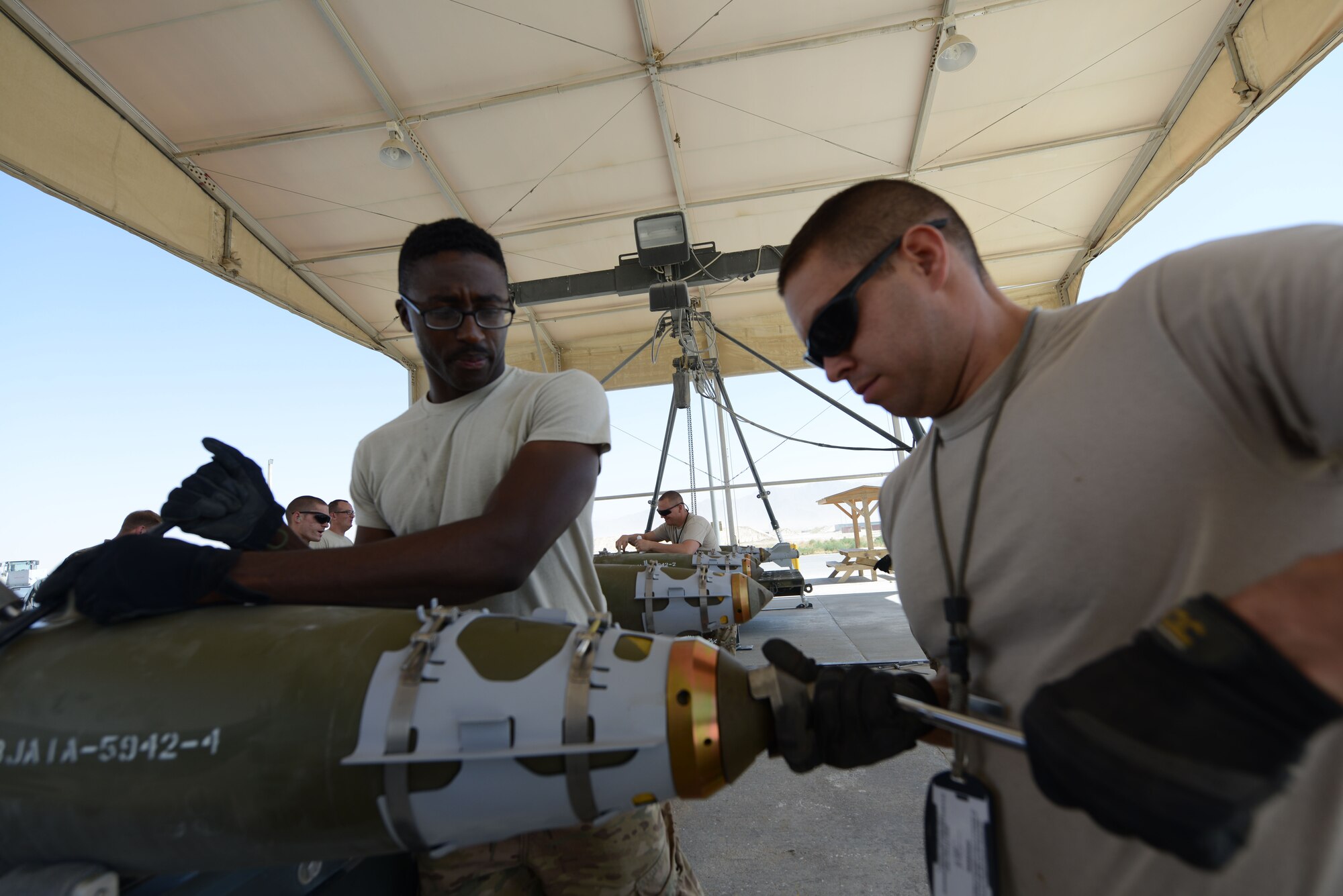 U.S. Air Force Staff Sgt. Terrin Love, a native of Montgomery, Ala., and Senior Airman William Spencer, a native of Kansas City, Mo., work together to tighten the tail end of a GBU-38 bomb at Bagram Airfield, Afghanistan Aug. 14, 2014. The GBU-38 is a vital part of the F-16C Fighting Falcon weapons system. Love, an Air National Guardsman is deployed from the 187th Fighter Wing in Montgomery, Ala., while Spencer, a reservist is a native of Kansas City, Mo. The Ammo team, an example of Total Force Integration, is comprised active duty, guard and reserve members. (U.S. Air Force photo by Master Sgt. Cohen A. Young/Released)