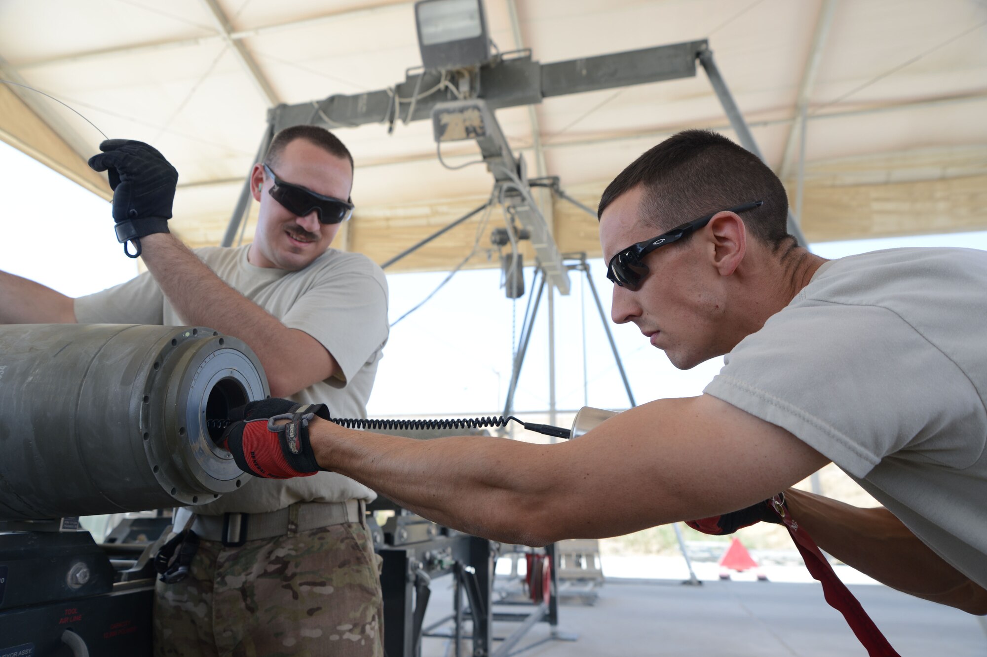 U.S. Air Force Senior Airman Christopher Reed, a munitions systems technician currently assigned to the 455th Expeditionary Maintenance Squadron, works with Senior Airman Brandon Graves, a munitions systems technician string connection wire through a bomb conduit to an initiator as they build a GBU-38 bomb at Bagram Airfield, Afghanistan Aug. 14, 2014. The GBU-38 is utilized by the F-16C Fighting Falcon. Reed and Graves are an example of total force integration. Both men are deployed from Whiteman Air Force Base, Missouri. Reed is an active duty member originally from Des Moines, Idaho, while Graves is a reservist originally from Kansas City, Kan.  (U.S. Air Force photo by Master Sgt. Cohen A. Young/Released)