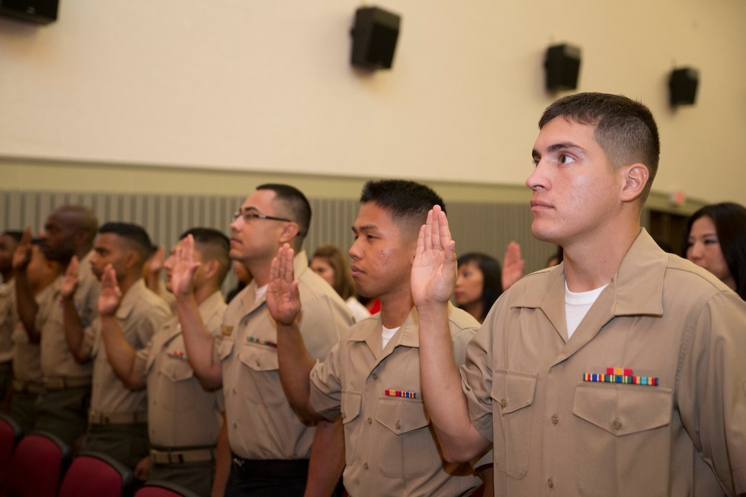 Service members and dependents raise their right hand during the Oath of Allegiance to become a U.S. citizen during the Naturalization Ceremony Aug. 22 at the Camp Foster Theater, Camp Foster, Okinawa, Japan. In a video presentation, President Barrack Obama congratulates the candidates for their efforts on becoming U.S. citizens. The ceremony consisted of 35 candidates from 21 different countries, including South Africa, Guatemala, Vietnam, Canada and Negros Oriental. The service members are with various units on Okinawa.