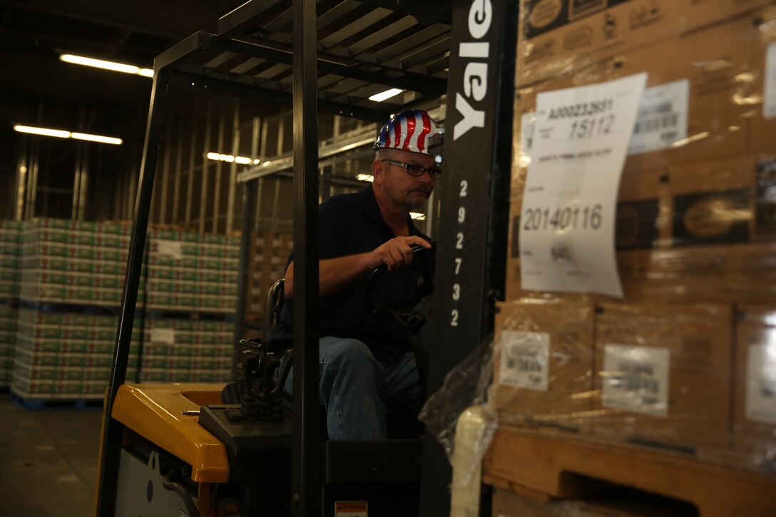 Bill Thompson, freight handler, Distribution Management Office, unloads a pallet of coffee at a loading dock for Operation Coffee Giveaway with donated Keurig cups and ground coffee from Holy Joe’s Café, Aug. 21, 2014.