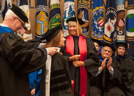 National Intelligence University President Dr. David Ellison confers an honorary Doctor of Strategic Intelligence degree to National Geospatial-Intelligence Agency Director Letitia Long at the opening convocation of the academic year Aug. 25 as NIU Provost Dr. Susan Studds and faculty members look on.
