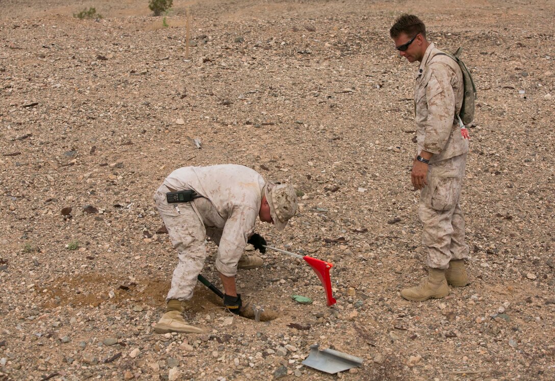 Staff Sgt. Robbie Grieder, left, an Explosive Ordnance Disposal technician team leader with Headquarters & Headquarters Squadron at Marine Corps Air Station Yuma, Ariz., and a native of Belle Plaine, Iowa, digs around unexploded ordnance before flagging it as Staff Sgt. Kyle Winjum, an EOD technician with Marine Wing Support Squadron 372 from Marine Corps Base Camp Pendleton, Calif., looks on during range clearance operations at the Chocolate Mountain Aerial Gunnery Range, Calif., Monday, Aug. 25, 2014.