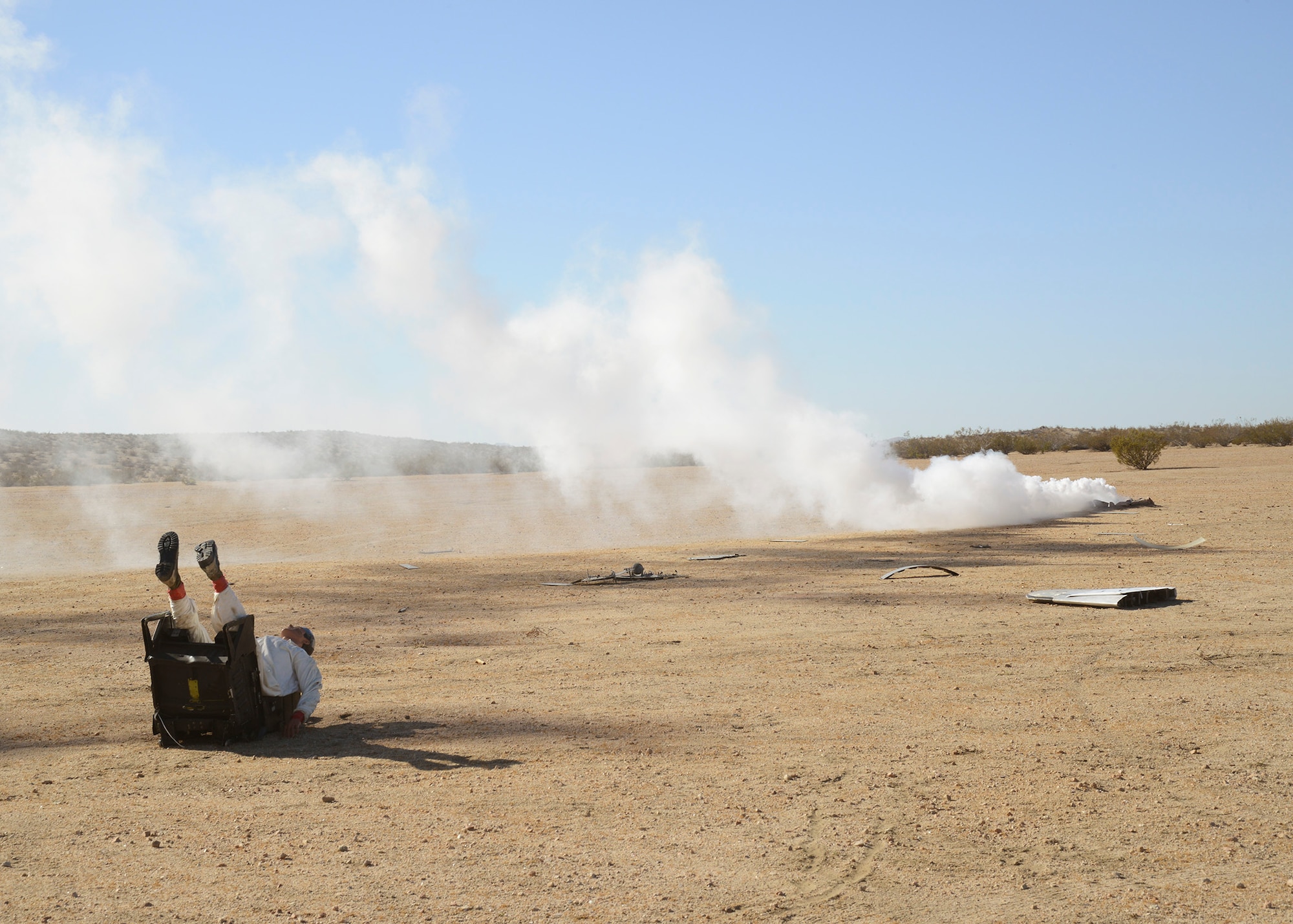 A dummy representing a downed pilot lies on the ground in the Mojave Desert, 14 miles east of California City Aug. 27. Smoke and plane parts were also present to represent the crash site of an F-16 for exercise Desert Wind 14-06, an emergency response and readiness exercise designed to practice how Edwards AFB responds to a crash off base. (U.S. Air Force photo by Kenji Thuloweit) 