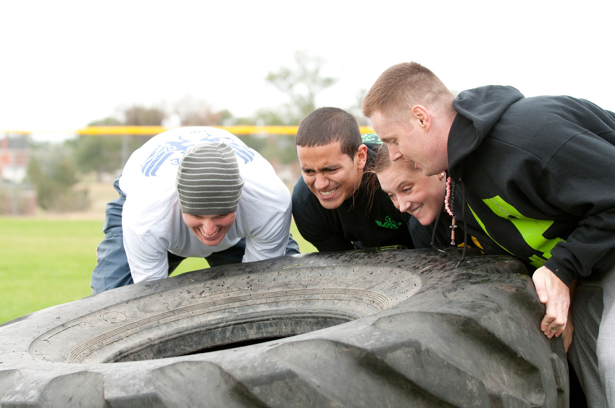 Team members representing 90th Force Support Squadron lift a 500 lb. tire as part of a Team Endurance Challenge during one of the events at Frontiercade on F.E. Warren Air Force Base, Wyo., Aug. 28, 2014. The Team Endurance Challenge required teams to lift a tire for a set distance, carry a log, and run a relay race for time. (U.S. Air Force photo by Lan Kim)
