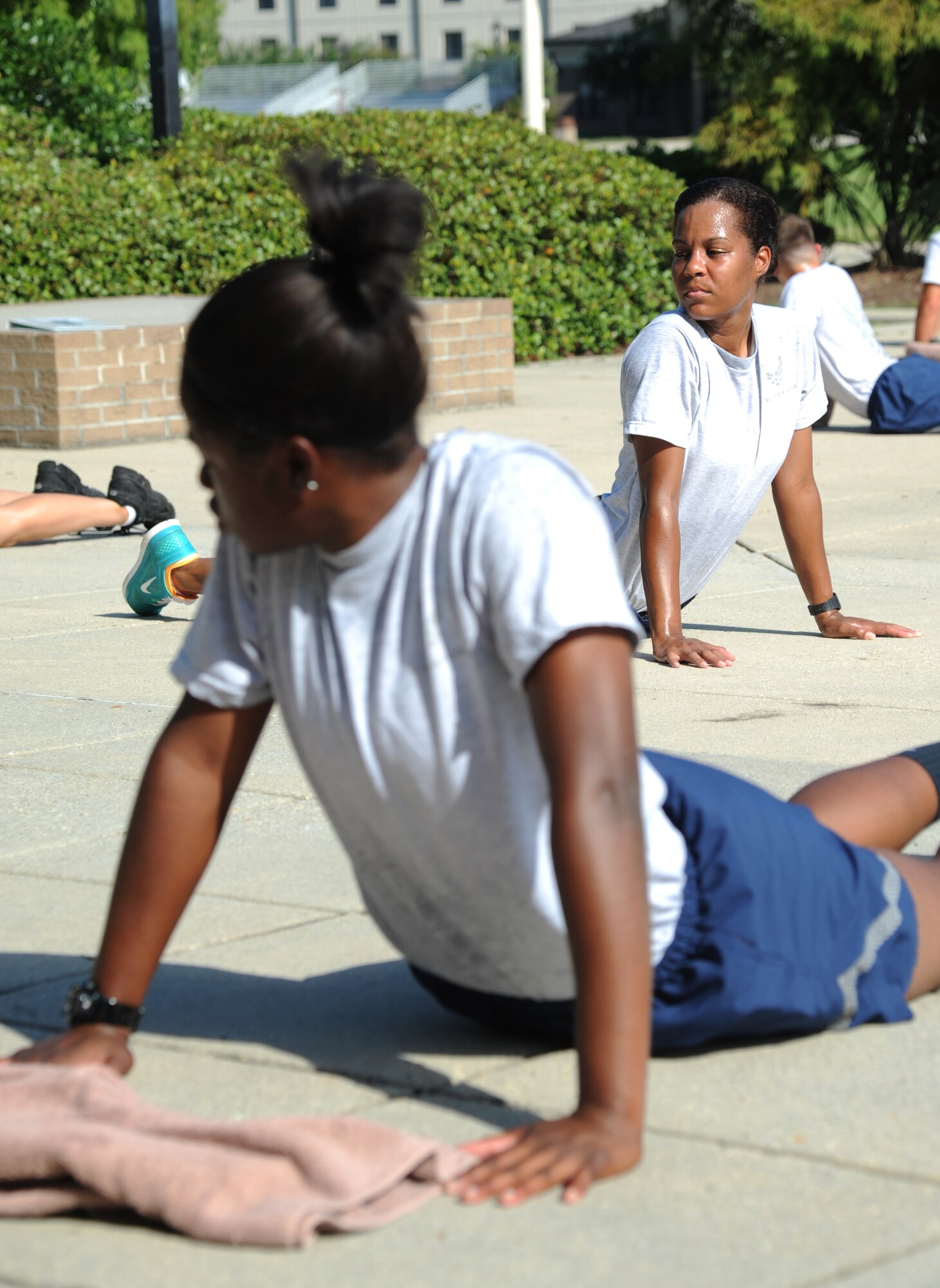 Airman Kalyn Crenshaw and Airman 1st Class Ashlee Rodriguez, 338th Training Squadron, participate in cool down stretches during a physical training session Aug. 27, 2014, in the triangle area, Keesler Air Force Base, Miss.  Physical training is a top priority for Airmen to be prepared and equipped for any physical challenge they may face when conducting the mission at home station or in a deployed environment. (U.S. Air Force photo by Kemberly Groue)