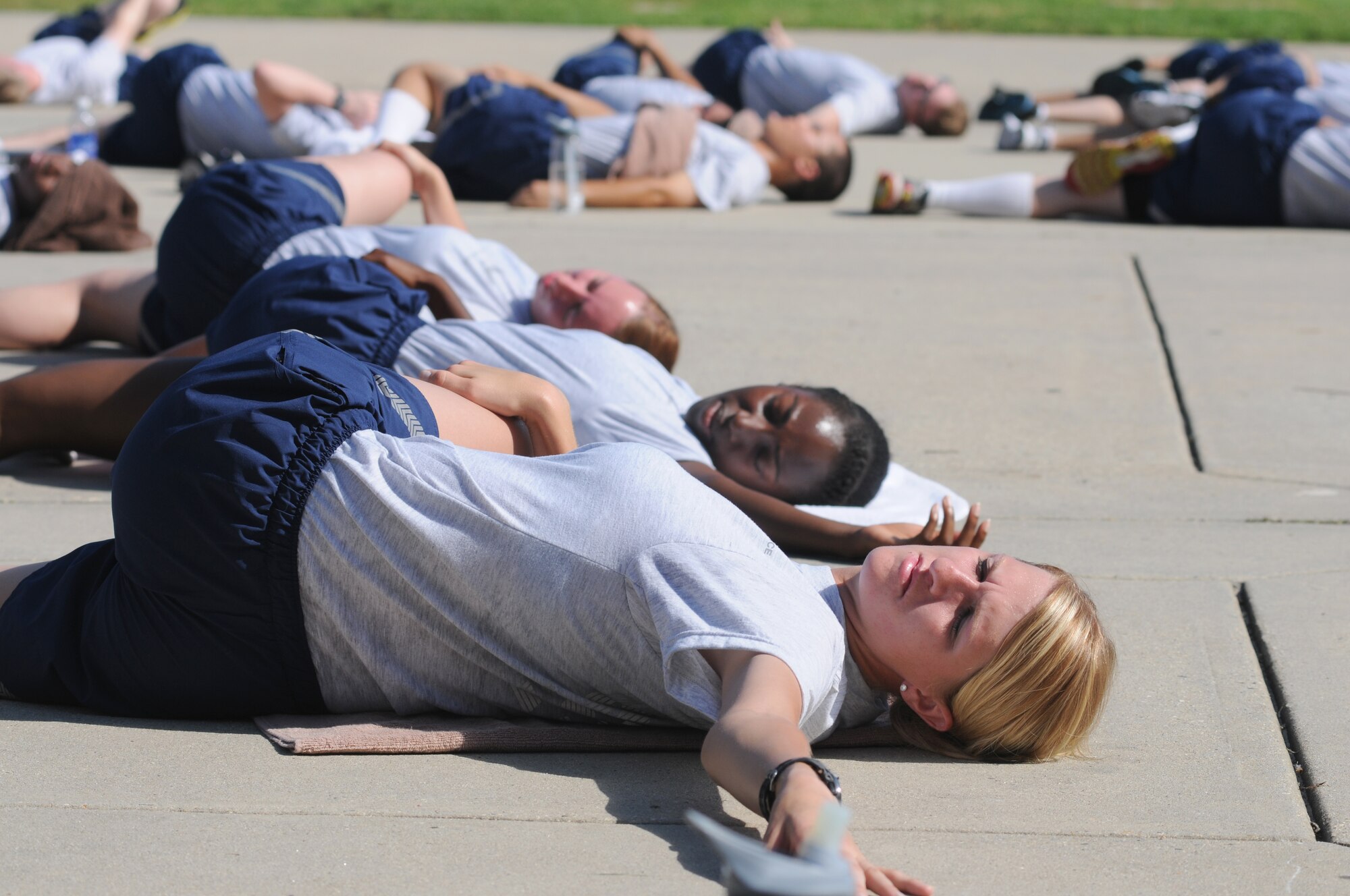 Airman Basic Emily Wagner, (foreground), 338th Training Squadron, participates in cool down stretches during a physical training session Aug. 27, 2014, in the triangle area, Keesler Air Force Base, Miss.  Physical training is a top priority for Airmen to be prepared and equipped for any physical challenge they may face when conducting the mission at home station or in a deployed environment.  (U.S. Air Force photo by Kemberly Groue)