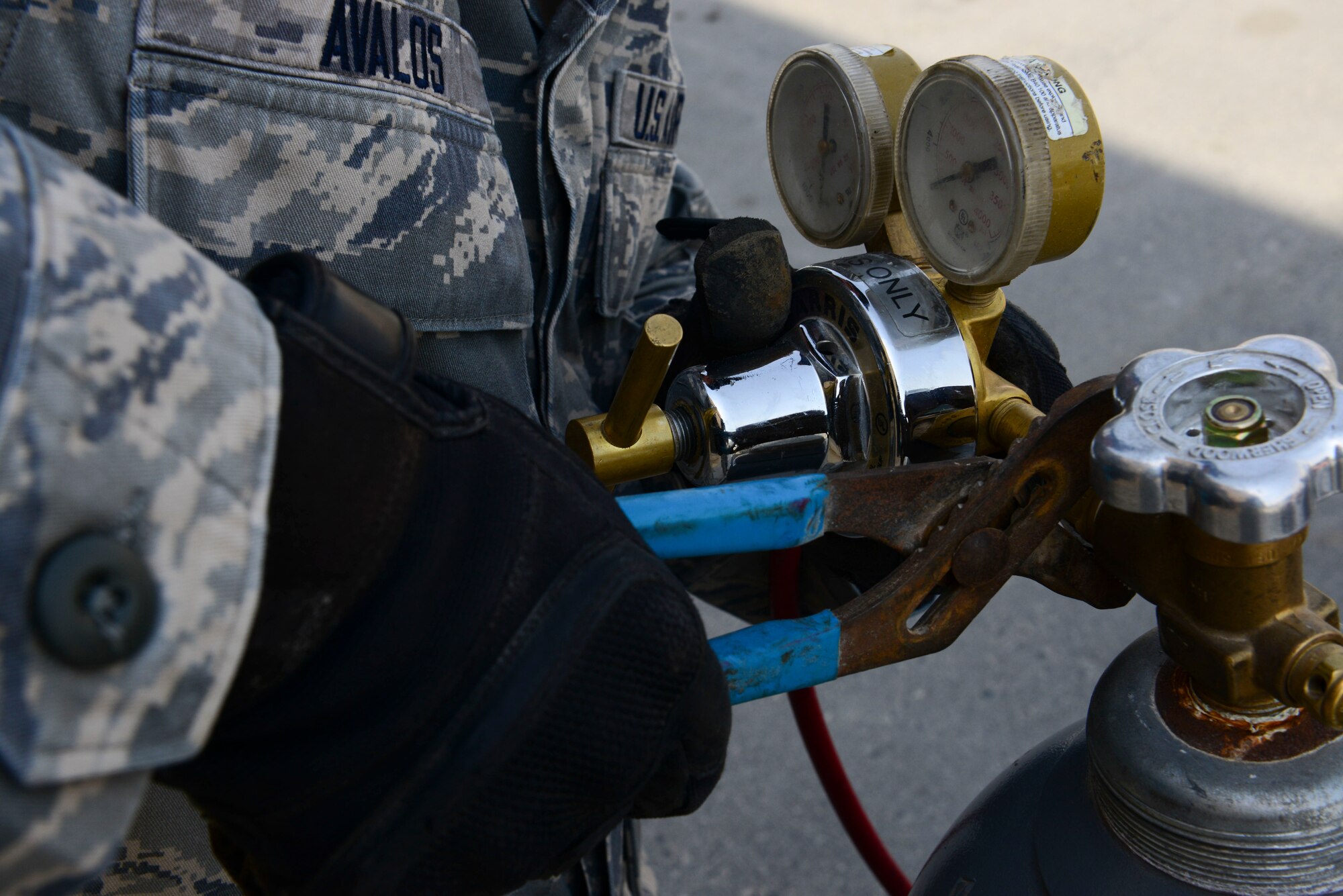 U.S. Air Force Airman 1st Class Cesar Avalos, 379th Expeditionary Civil Engineer Squadron heating ventilation and air conditioning journeyman, turns on a nitrogen gas tank at Al Udeid Air Base, Qatar, Aug. 28, 2014. The nitrogen gas is run through the air conditioning unit’s lining of a building for a short period of time to find the source of where there may be a break in the flow of air. Avalos is deployed here from Travis Air Force Base, California and hails from Yuma, Arizona. (U.S. Air Force photo by Staff Sgt. Ciara Wymbs/Released)