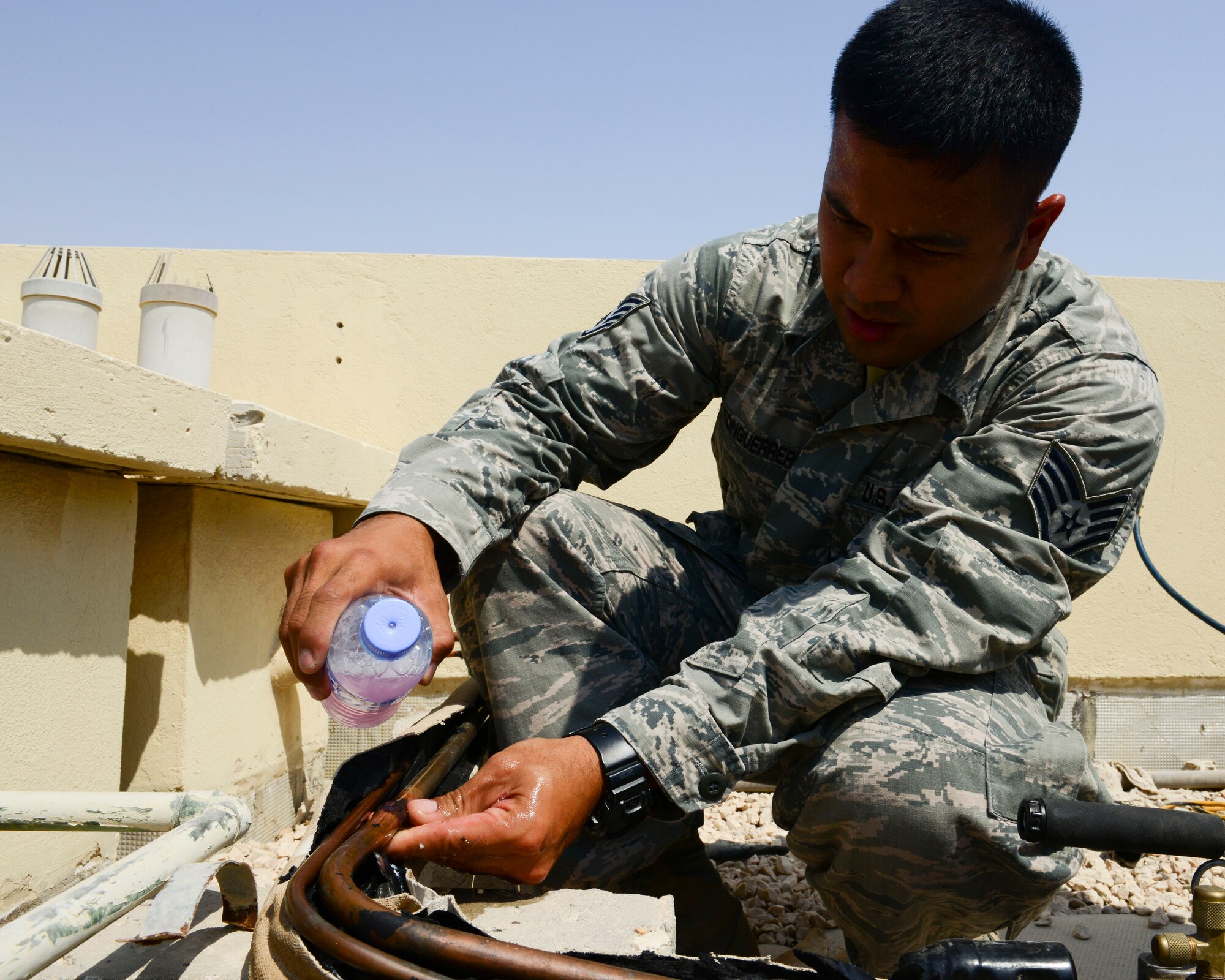 U.S. Air Force Staff Sgt. Gerald Leon Guerrero, 379th Expeditionary Civil Engineer heating ventilation and air conditioning craftsman, pours soapy water onto copper pipes at Al Udeid Air Base, Qatar, Aug. 28, 2014. The soapy water creates bubbles that indicate where there a leak may originate in the pipes. Leon Guerrero is from Tamuning, Guam, and is deployed from Cannon Air Force Base, New Mexico. (U.S. Air Force photo by Staff Sgt. Ciara Wymbs/Released)
