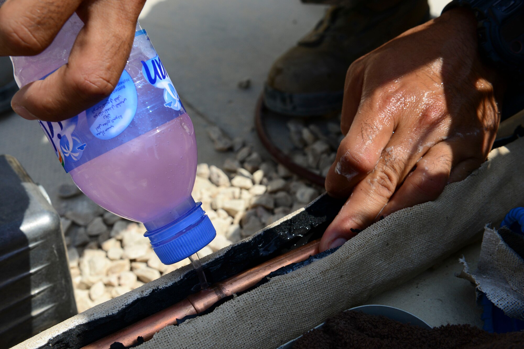 U.S. Air Force Staff Sgt. Gerald Leon Guerrero, 379th Expeditionary Civil Engineer heating ventilation and air conditioning craftsman, pours soapy water onto a copper pipe at Al Udeid Air Base, Qatar, Aug. 28, 2014. The opening is created to gain a better view of the copper pipes underneath, to find the source of an air conditioning unit’s problems. Leon Guerrero is from Tamuning, Guam, and is deployed from Cannon Air Force Base, New Mexico. (U.S. Air Force photo by Staff Sgt. Ciara Wymbs/Released)