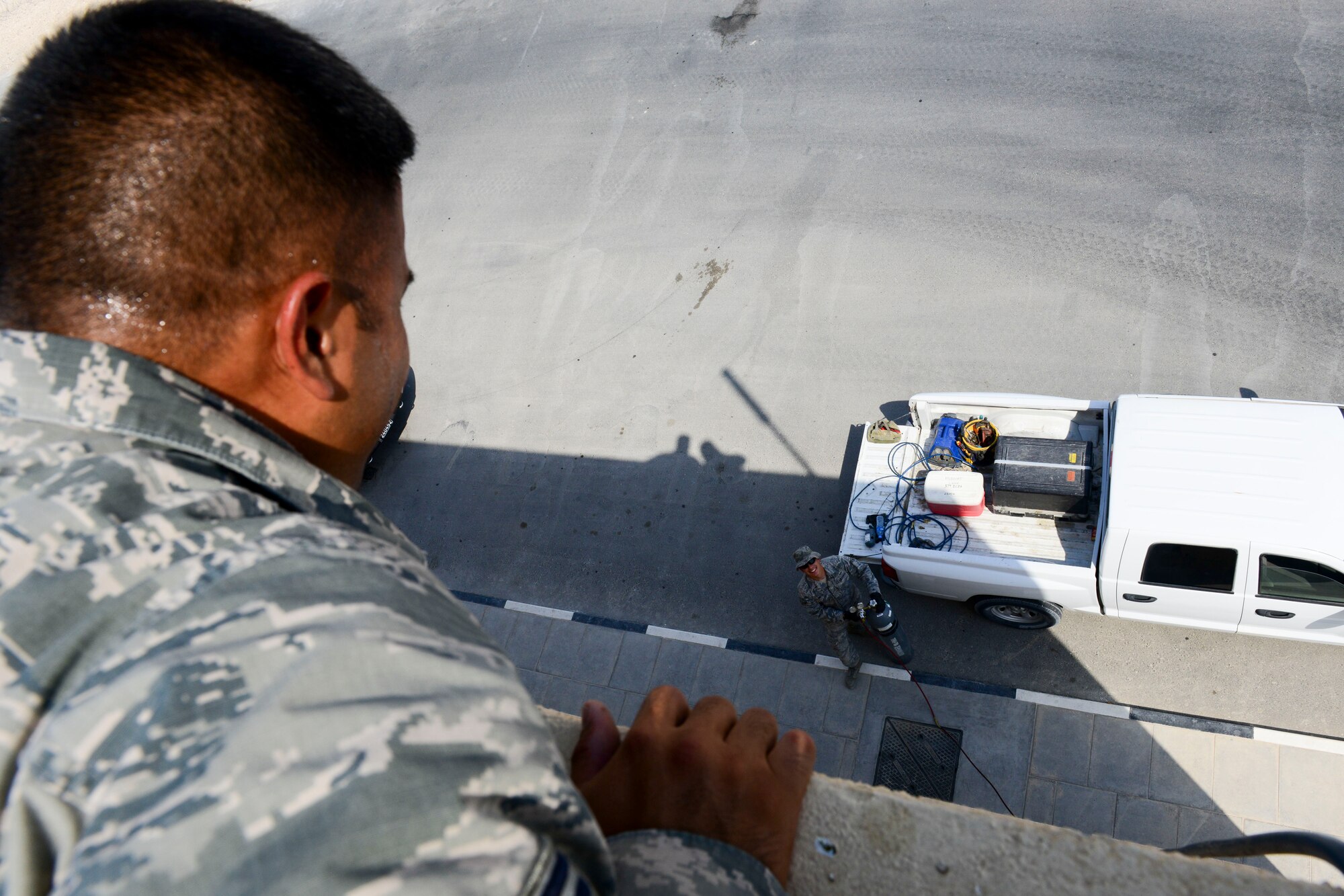 U.S. Air Force Staff Sgt. Gerald Leon Guerrero, 379th Expeditionary Civil Engineer heating ventilation and air conditioning craftsman throws a line down for nitrogen gas to Airman 1st Class Cesar Avalos, 379th ECES heating ventilation and air conditioning journeyman, at Al Udeid Air Base, Qatar, Aug. 28, 2014. The nitrogen gas is used to find the source of where there may be a break in cool air. Leon Guerrero is from Tamuning, Guam, and is deployed from Cannon Air Force Base, New Mexico. Avalos is deployed here from Travis Air Force Base, California, and hails from Yuma, Arizona. (U.S. Air Force photo by Staff Sgt. Ciara Wymbs/Released)