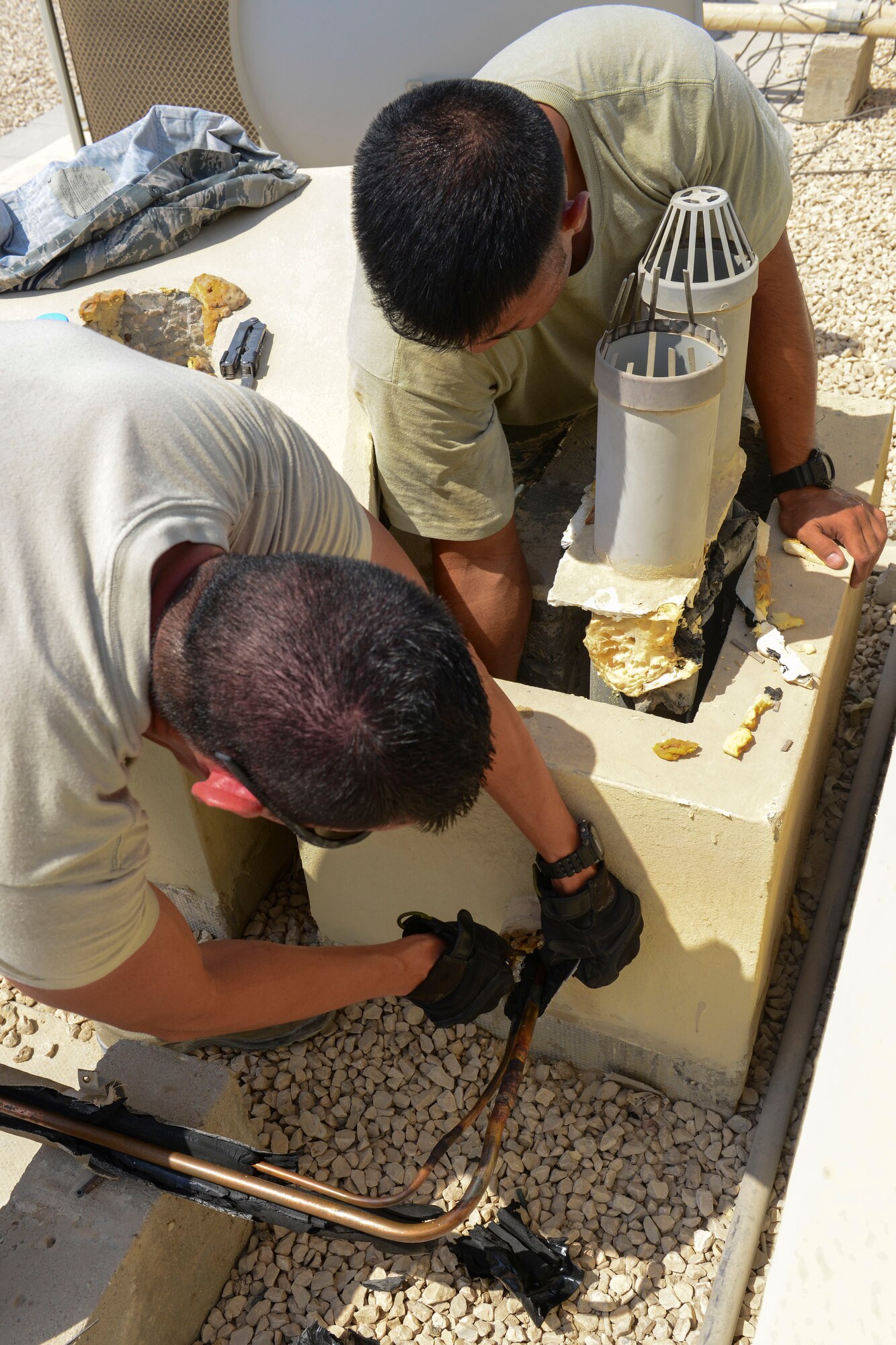 U.S. Air Force Airman 1st Class Cesar Avalos, left, and Staff Sgt. Gerald Leon Guerrero, 379th Expeditionary Civil Engineer heating ventilation and air conditioning specialists, work to find the source of an air conditioning unit leak at Al Udeid Air Base, Qatar, Aug. 28, 2014. The HVAC shop logs more than 900 work orders per month here during the summer months. Leon Guerrero is from Tamuning, Guam, and is deployed from Cannon Air Force Base, New Mexico. Avalos is deployed here from Travis Air Force Base, California and hails from Yuma, Arizona. (U.S. Air Force photo by Staff Sgt. Ciara Wymbs/Released)