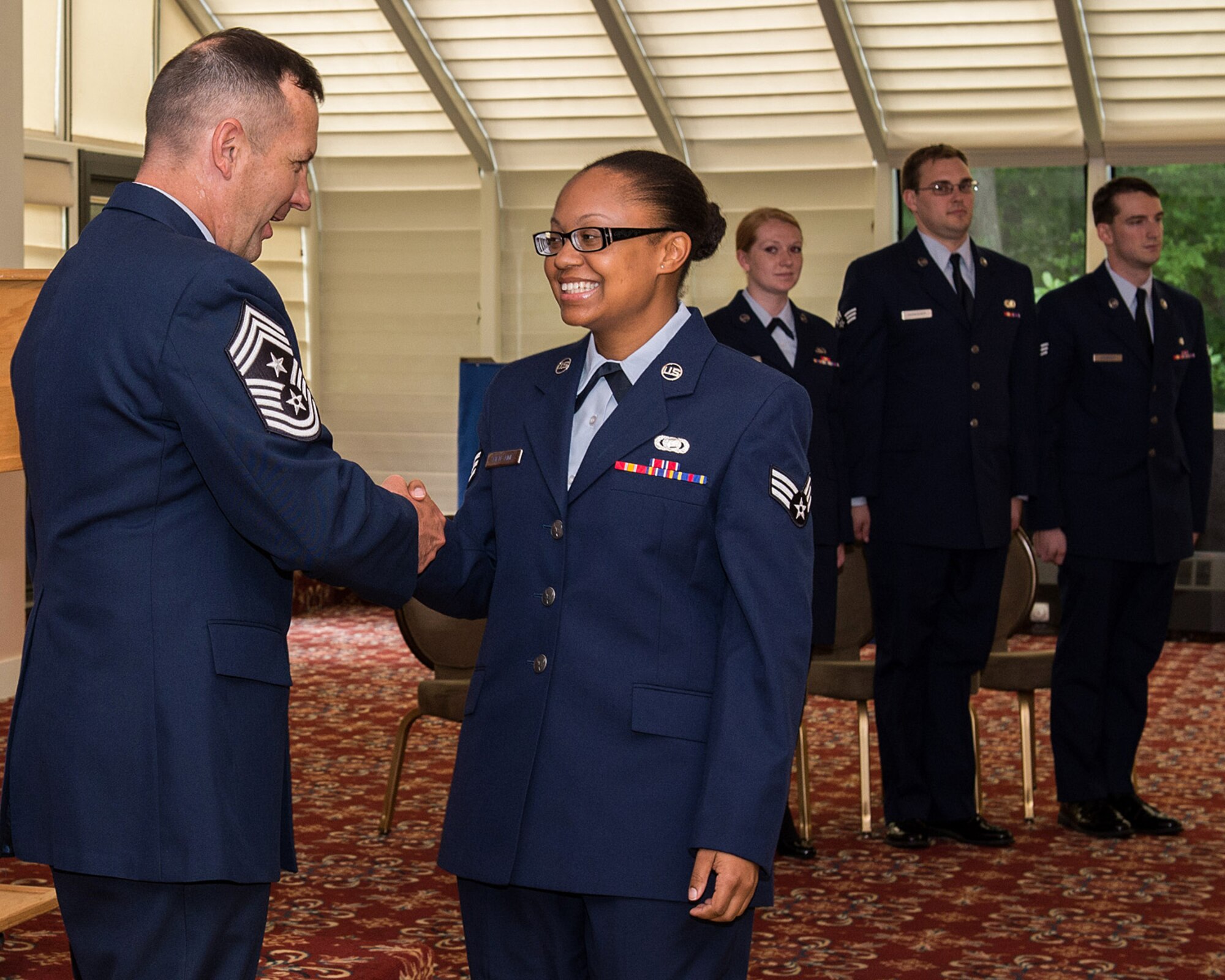 Command Chief Master Sgt. Craig A. Poling congratulates newly promoted Senior Airman Sabine Bien-Aime during the monthly enlisted promotion ceremony at the Minuteman Commons Aug 28. The monthly enlisted promotion ceremony, generally held the last duty day of the month gives the Hanscom community a chance to recognize enlisted Airman selected for promotion. (U.S. Air Force photo by Mark Herlihy)