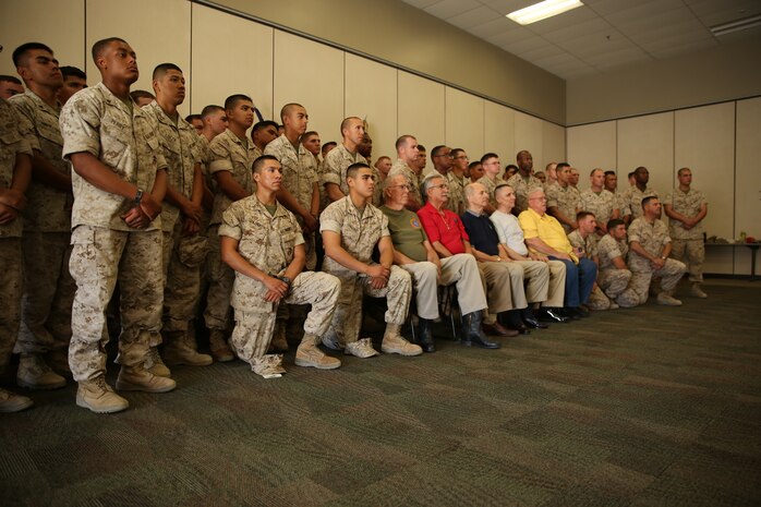 Members of the 1st Marine Division Association, Phoenix Chapter, sit with Marines with E Co., 2nd Battalion, 7th Marine Regiment, during the coin presentation ceremony at Building 1707 aboard the Combat Center, Aug. 22, 2014.