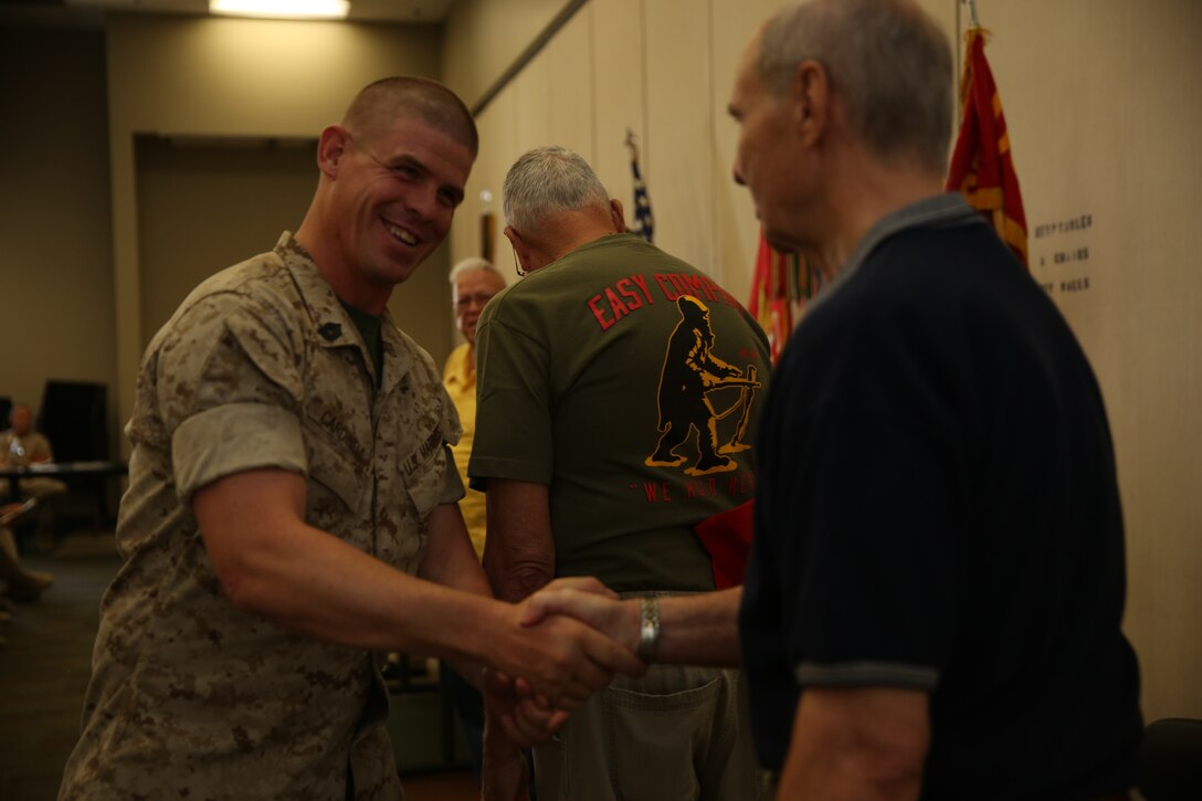 Gene Wuestenfield, president, Phoenix Chapter, 1st Marine Division Association, Phoenix Chapter, presents a coin to Gunnery Sgt. Kelly M. Cardinell, infantry unit leader, 2nd Battalion, 7th Marine Regiment, during a ceremony at building 1707 aboard the Combat Center, Aug. 22, 2014.