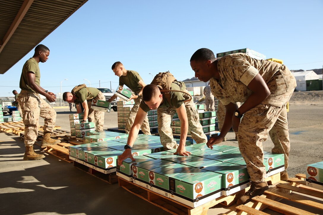 Marine Corps Communication-Electronics School students help redistribute boxes of coffee onto new pallets at a loading dock for Operation Coffee Giveaway with donated Keurig cups and ground coffee from Holy Joe’s Café, Aug. 21, 2014.